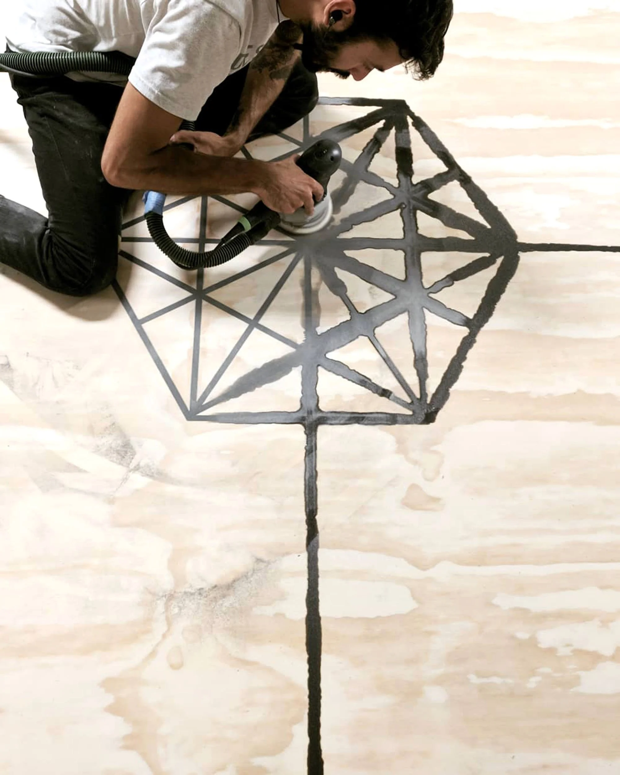Tecture AF fabricator working on a custom wood table, sanding the Tecture logo made from a resin inlay.