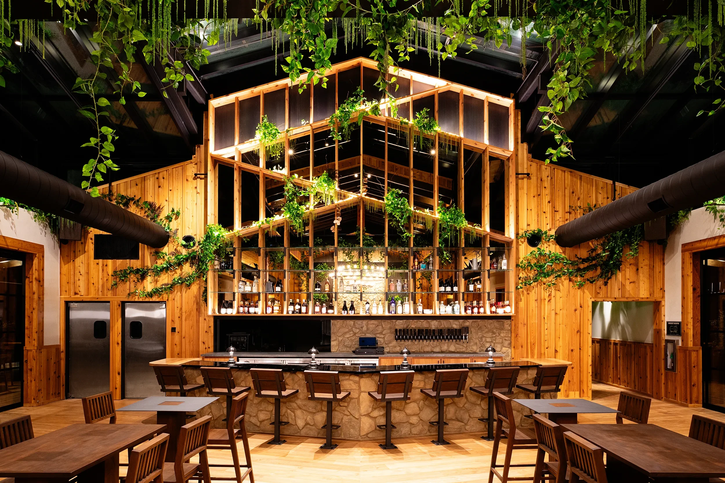 Stone faced bar, custom black resin bar top and gabled structure hung with greenery at Fox Point Farms in Encinitas
