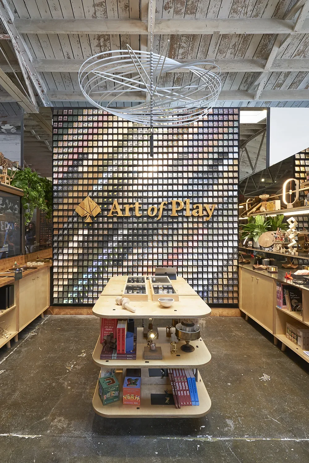 Art of Play in San Diego's Little Italy, with a custom playing-card display wall, wood brand lettering, and a central display table.