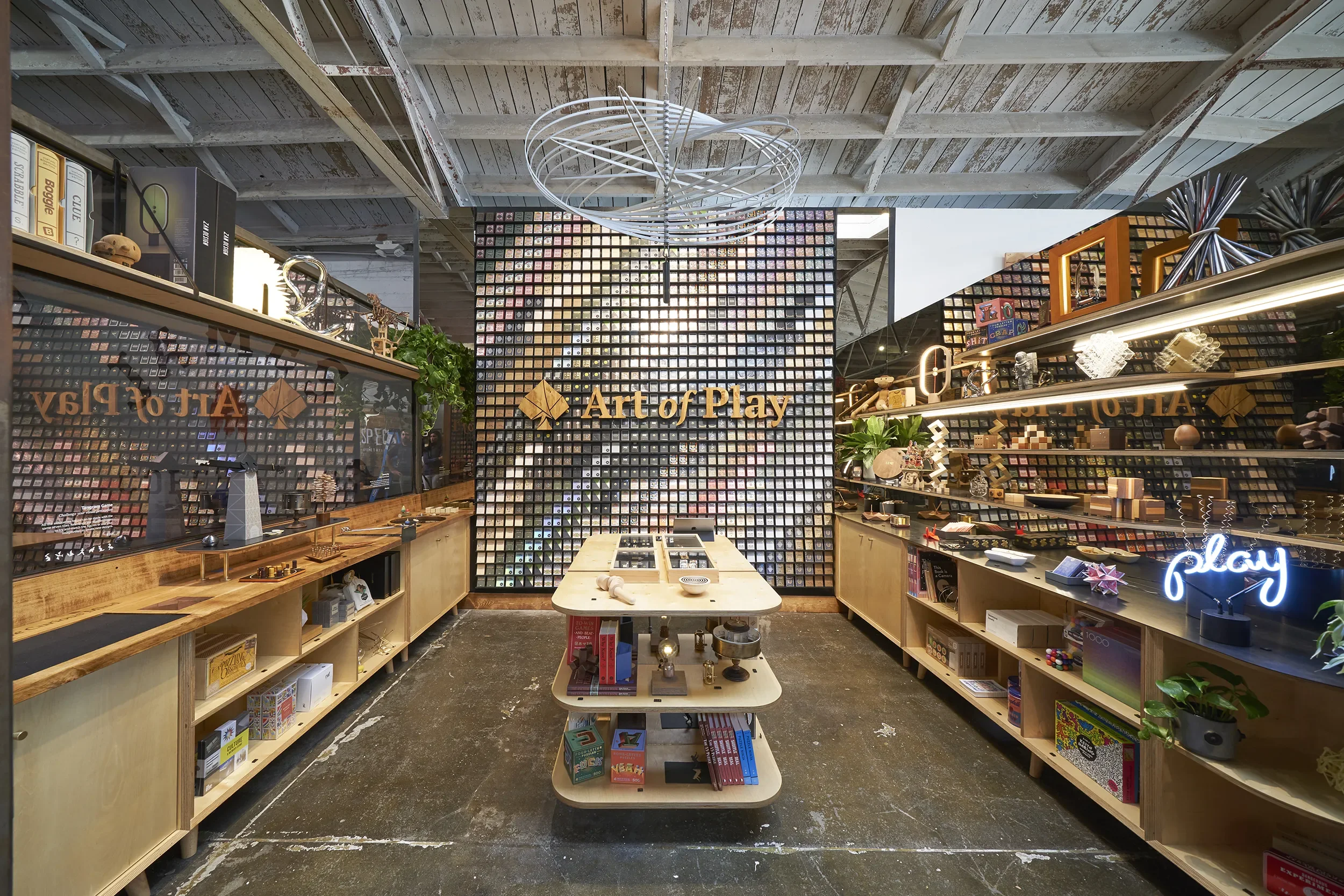 Backlit chainmail display wall and timber game shelving at Art of Play in Little Italy, San Diego
