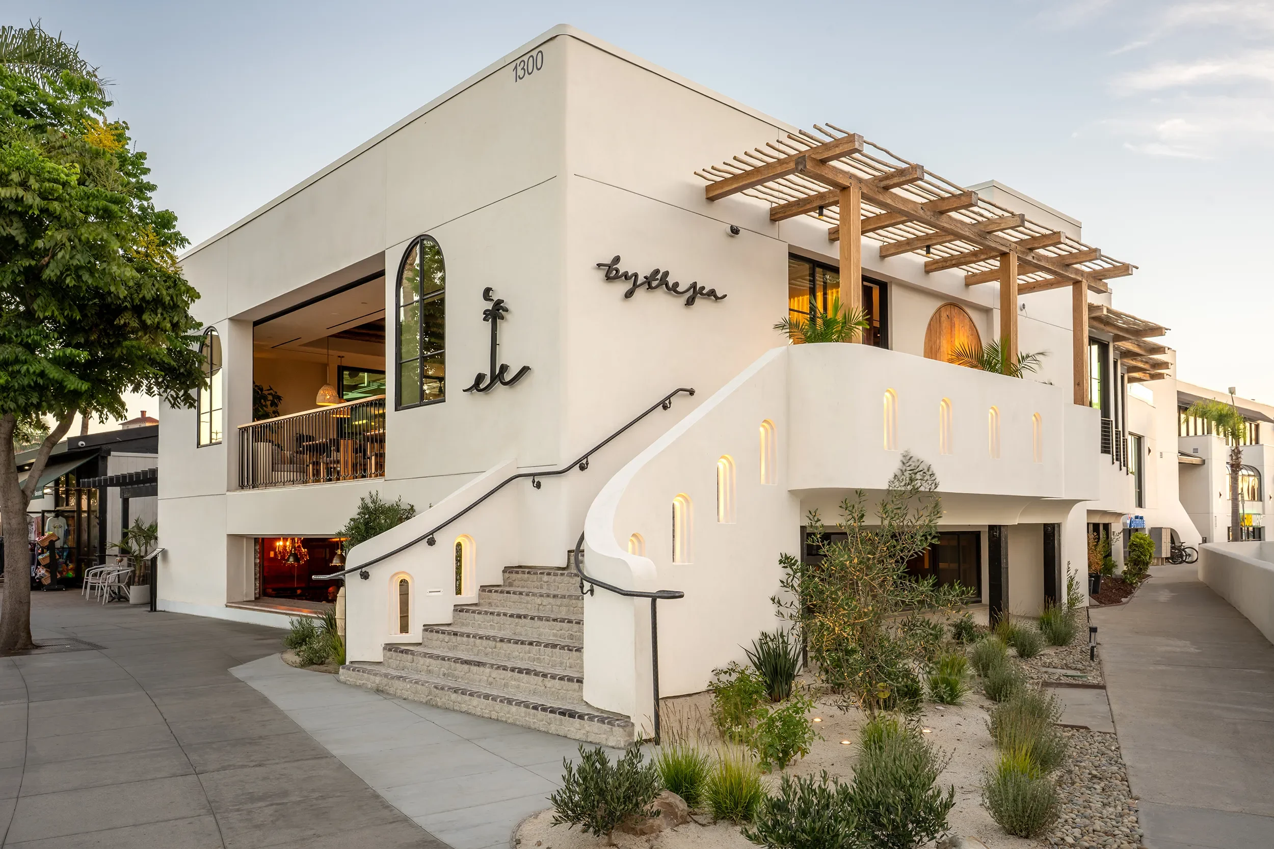Exterior of By The Sea at 1300 Orange Avenue in Coronado with script signage and a curved stair to the second floor