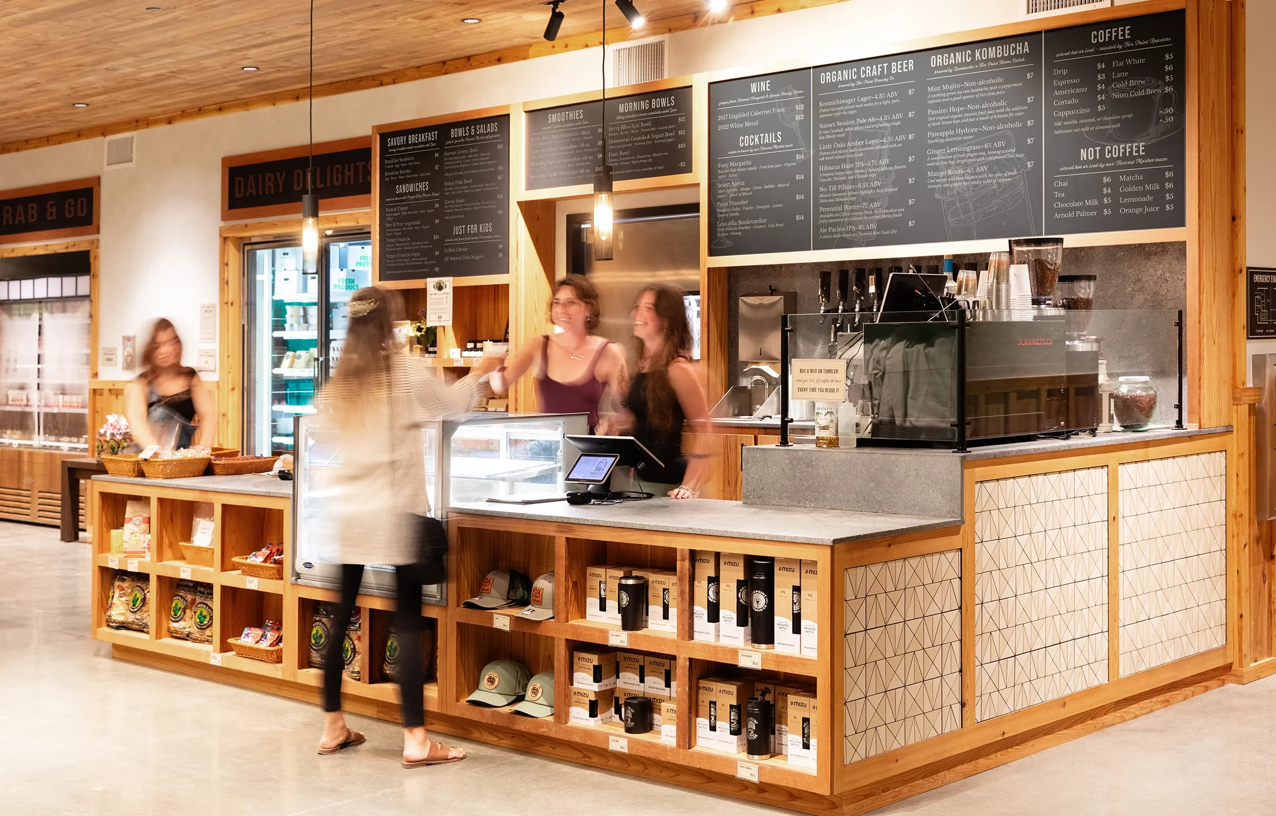Coffee counter at Fox Point Farms in Encinitas, with wood merchandise shelving , geometric tile panels, and overhead menu boards.