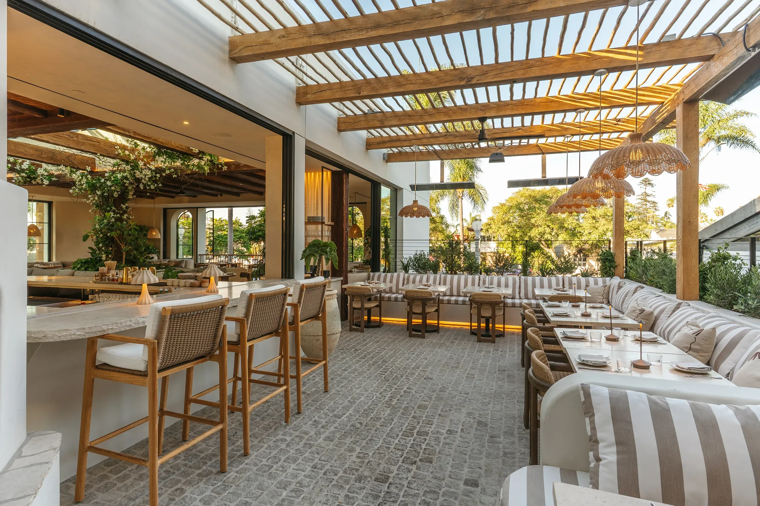 Eucalyptus wood trellis over the terrace bar at By The Sea with counter stools and white and beige striped banquettes