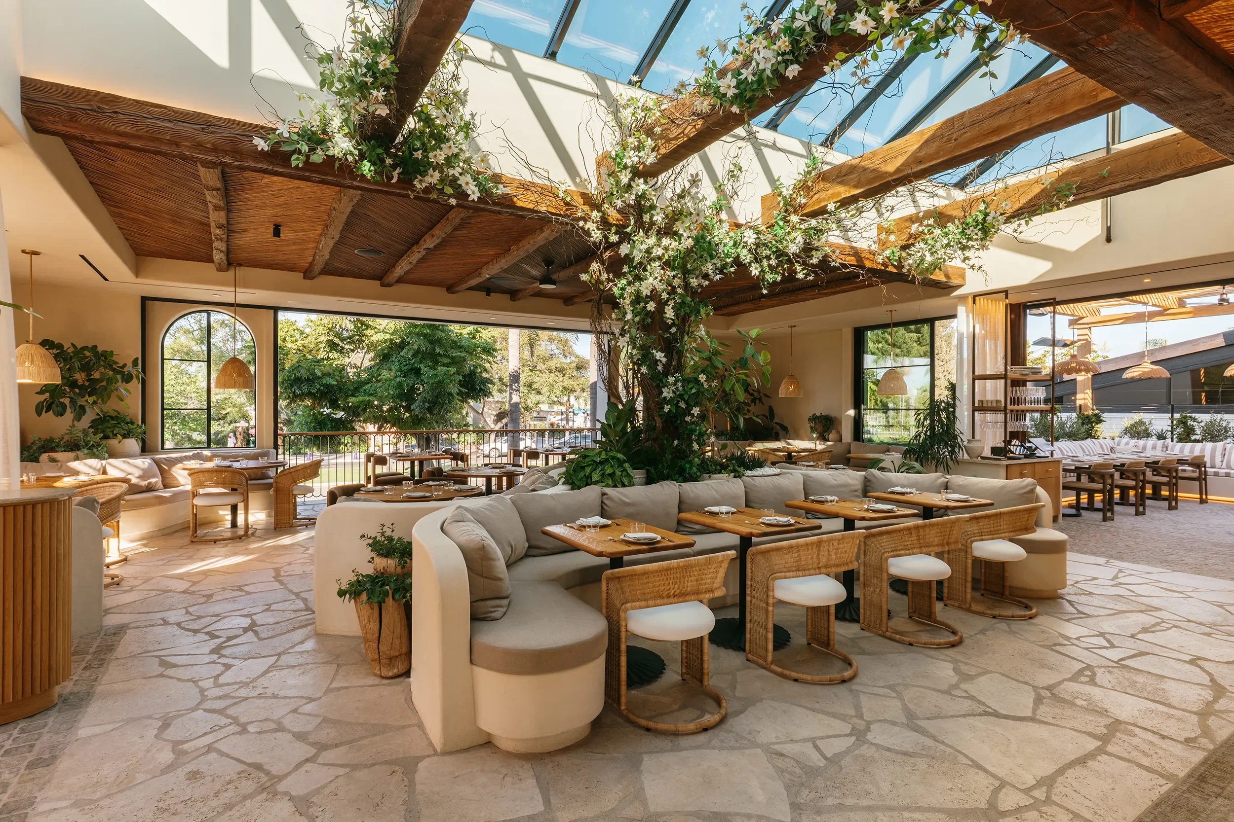 Skylit atrium dining room at By The Sea with flowering vine over reclaimed trusses and curved banquette