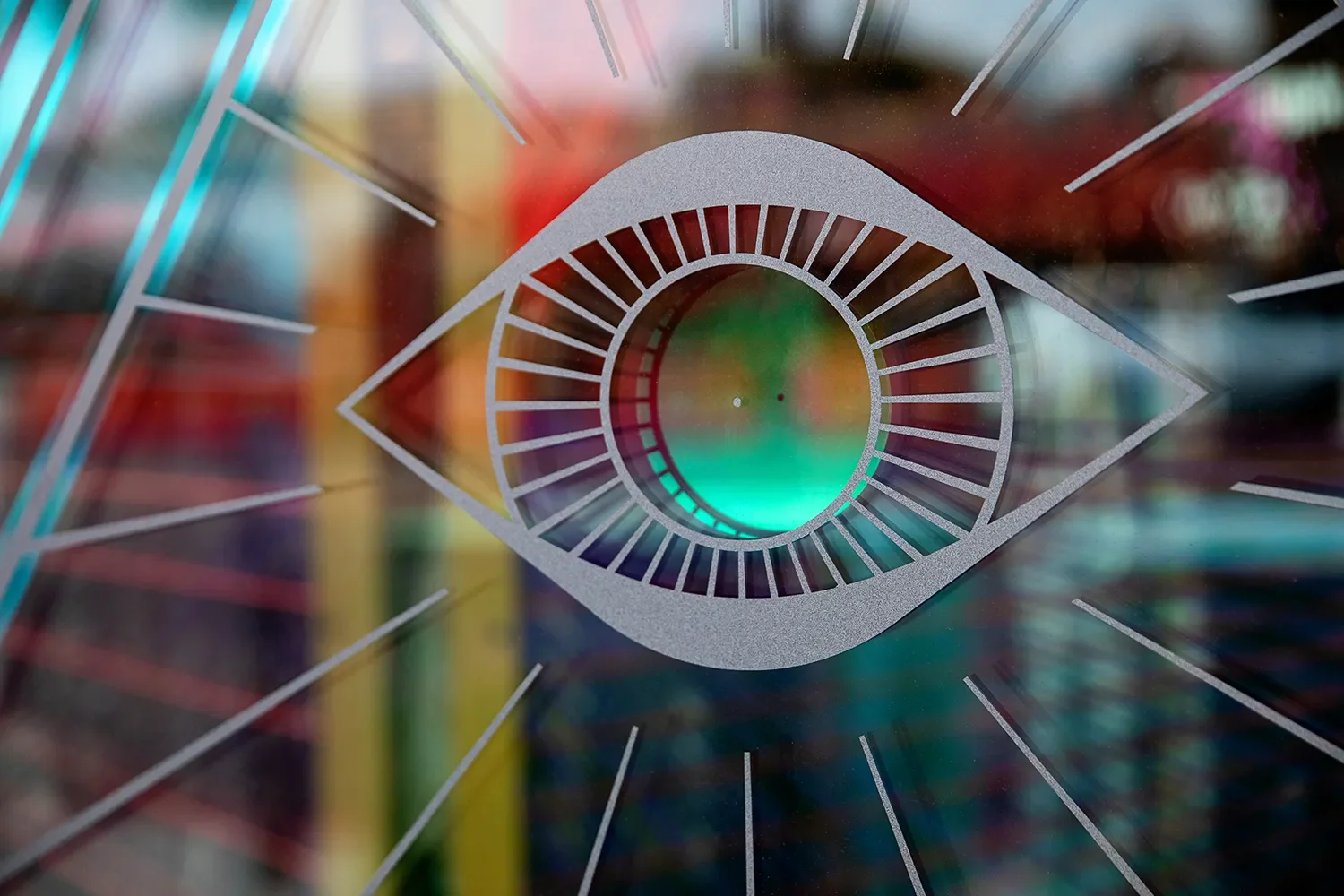 Gypsy Feather's eye emblem on an iridescent storefront window, with radiating lines and colorful reflections.
