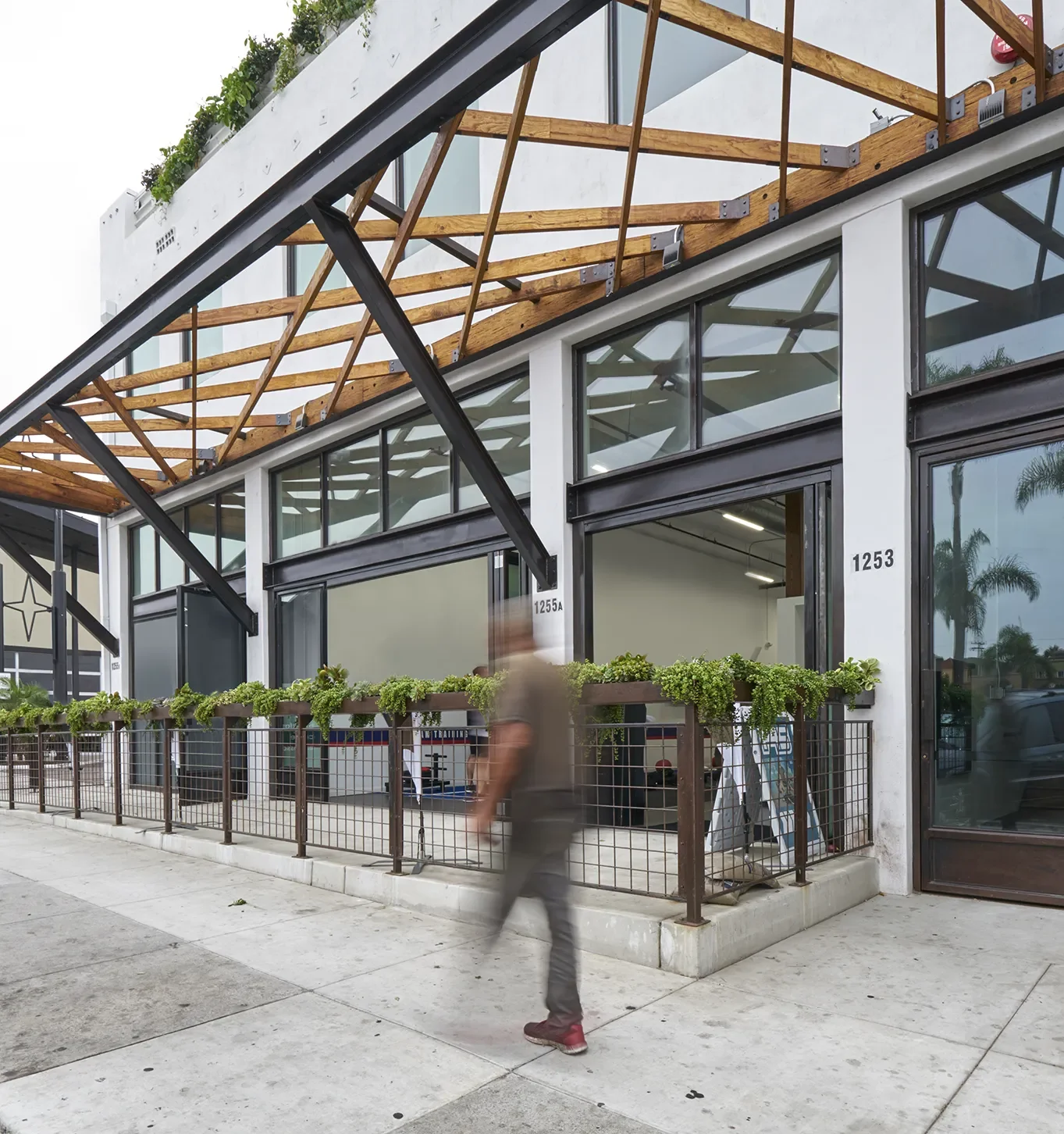 Uni Office Building exterior with a metal mesh fence, open glass doors, and a wood awning.