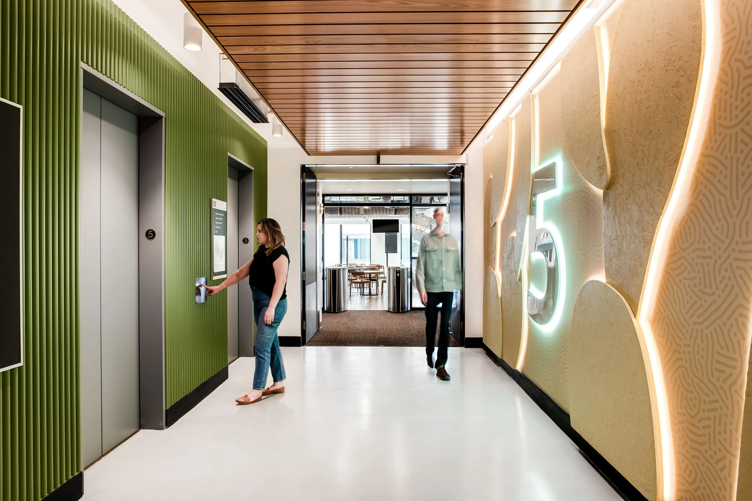 Commercial elevator lobby with illuminated floor number and sculptural layered backlit wall installation.