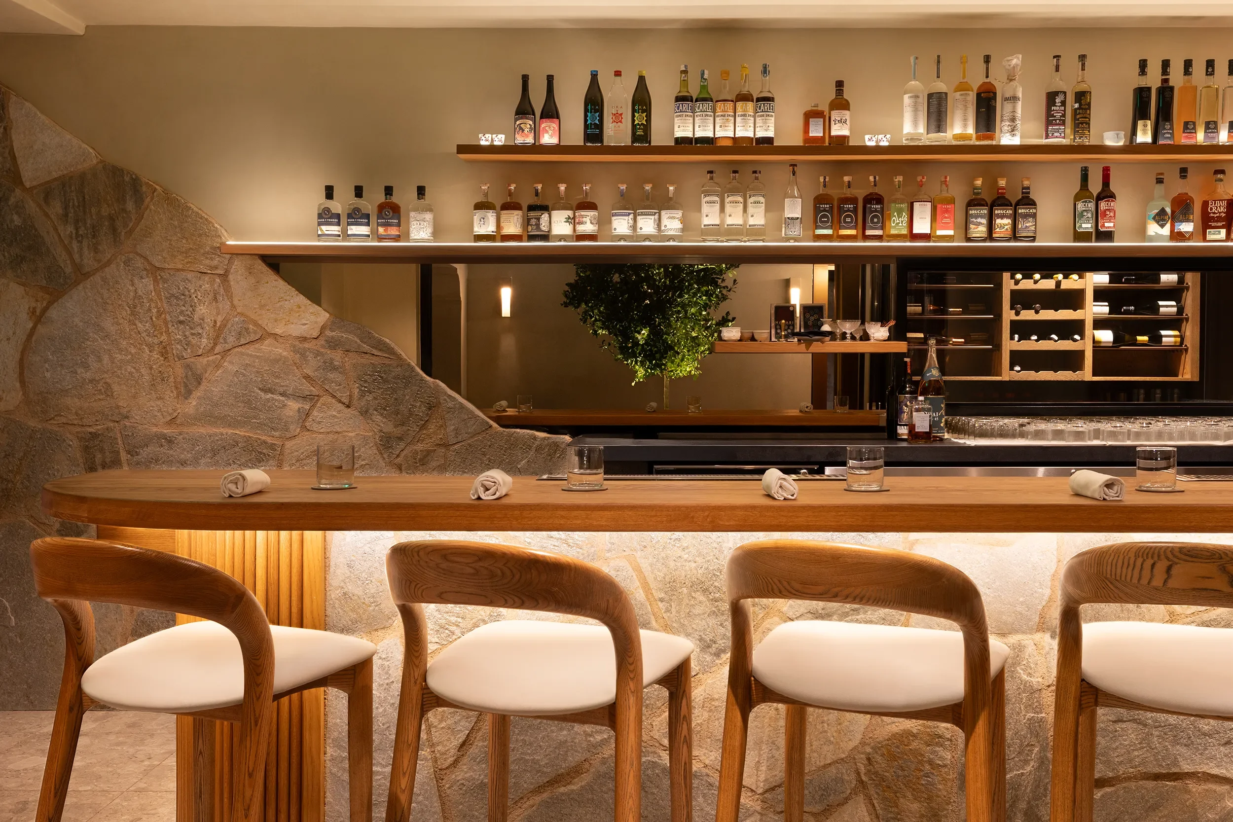 Stone bar bottle shelving with uplighting at Lucien, a small reservation only restaurant in La Jolla, San Diego