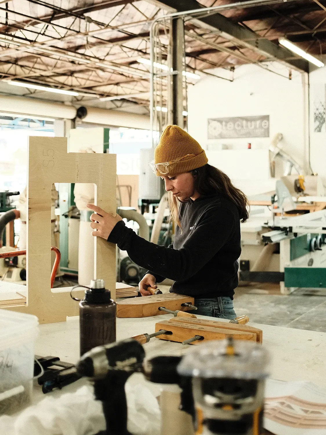 Devyn Bervid assembling a custom wood component at a workbench in the Tecture AF shop