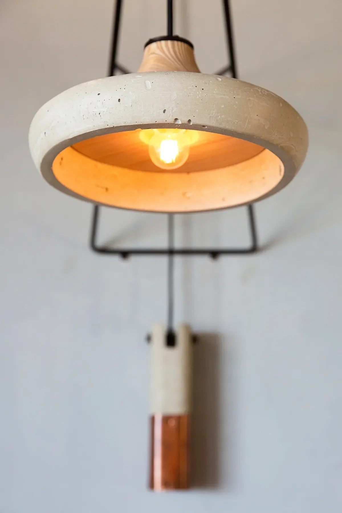 A concrete dome pendant with a warm bulb and black metal and brass detailing at Georges At The Cove in La Jolla 