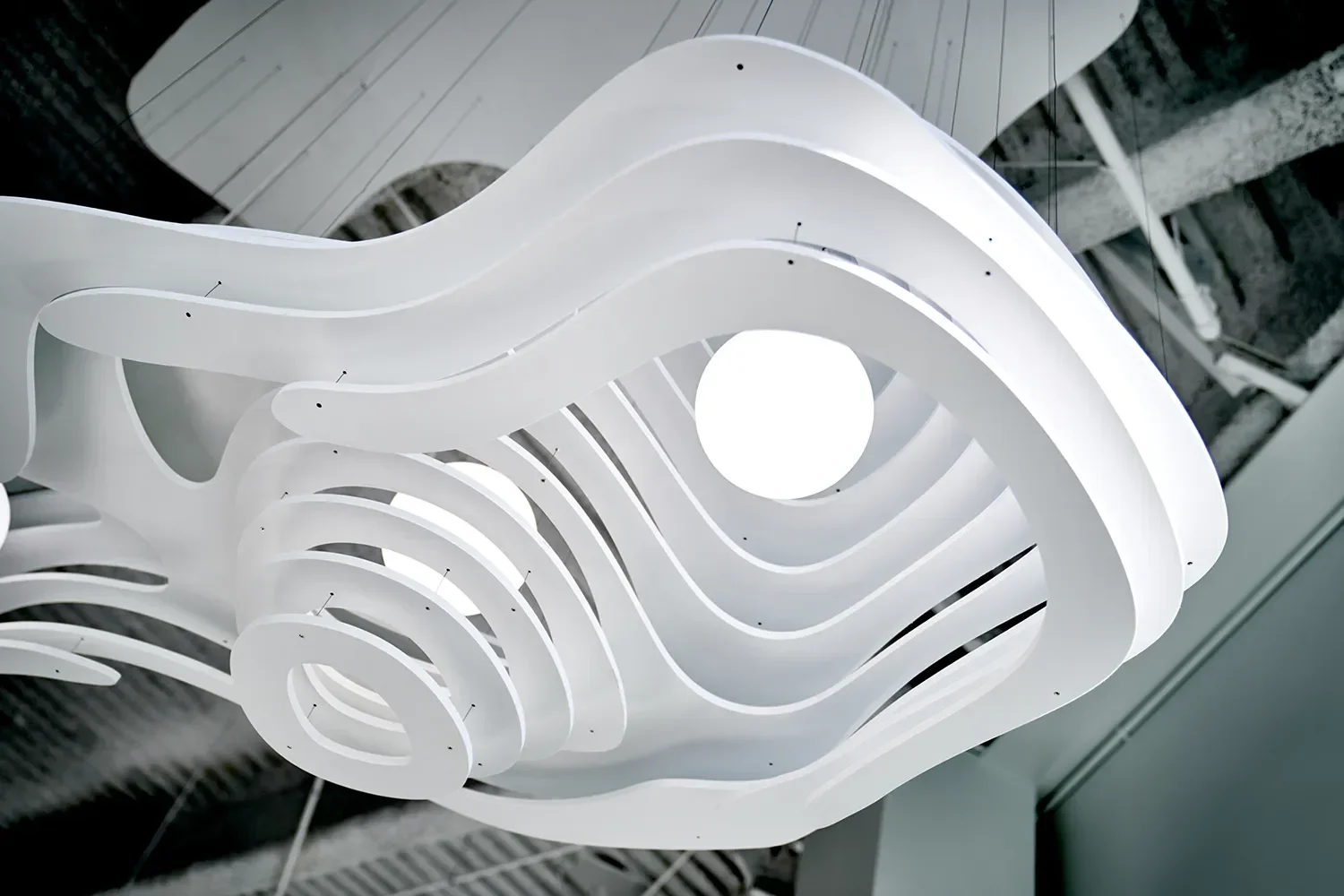 Cloud Light is a sculptural layered white chandelier with the bulb set inside carved topographical rings