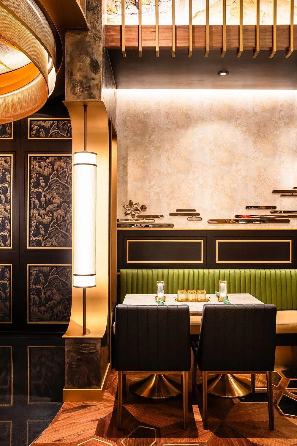 Dining banquette with green upholstery, a backlit wall and a large scale brass light feature integrated into the architecture