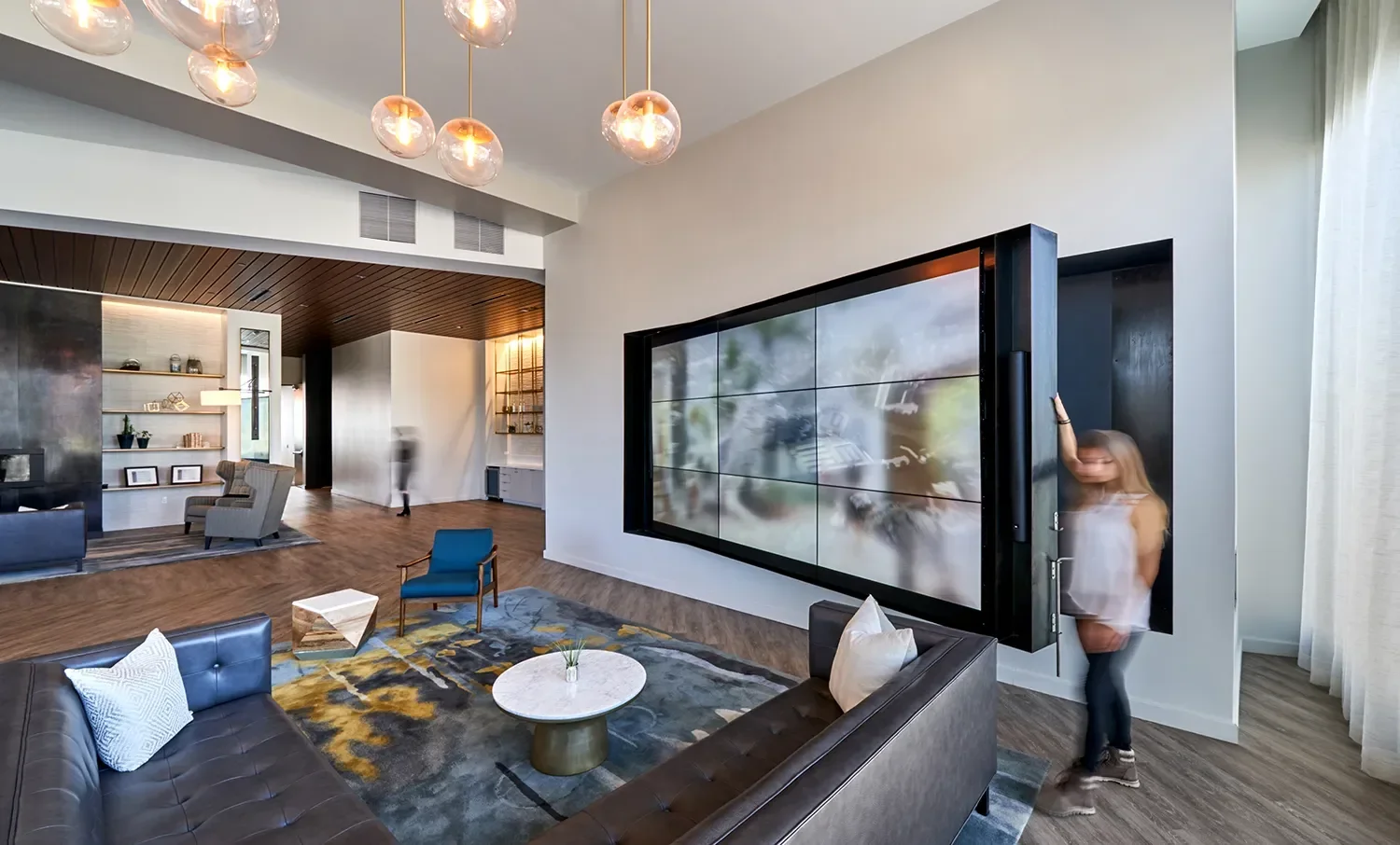 Custom framed media wall in a San Diego office space with pendant globe lights above the lounge area
