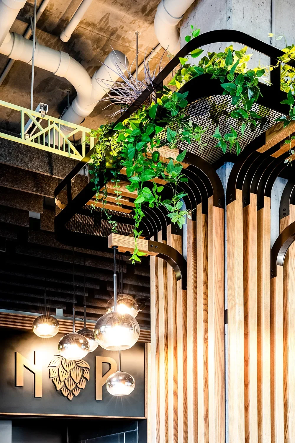 Arched wood slat column cladding with integrated lighting and plant shelf with plants overhead at North Park Beer Co in Bankers Hill San Diego