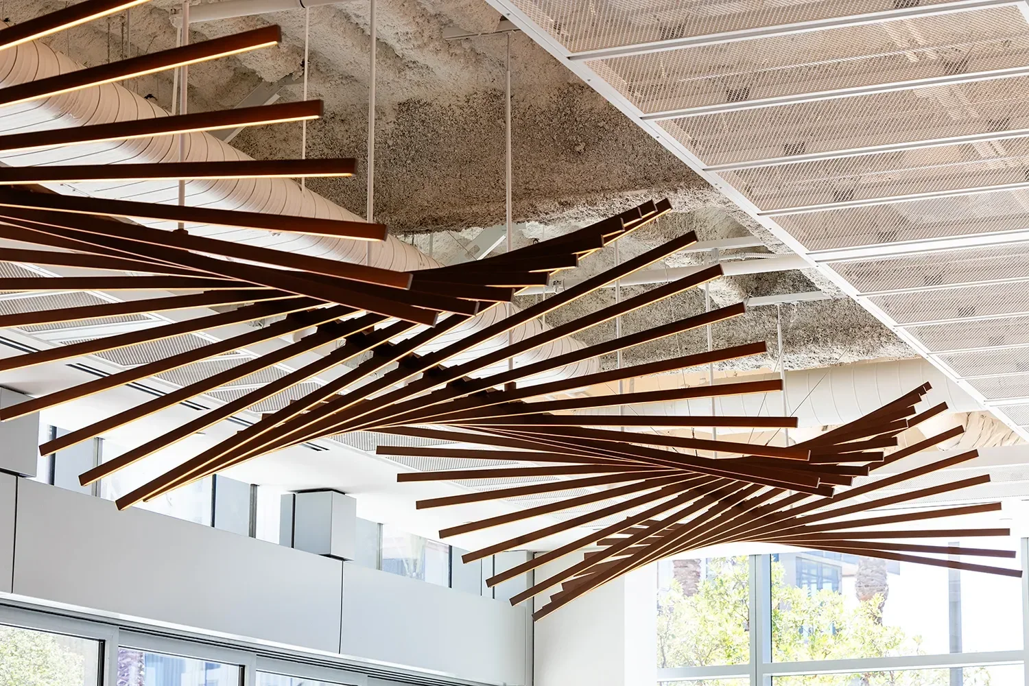 Suspended metal rod with integrated lighting installation suspended above the lobby of a commercial building in San Diego