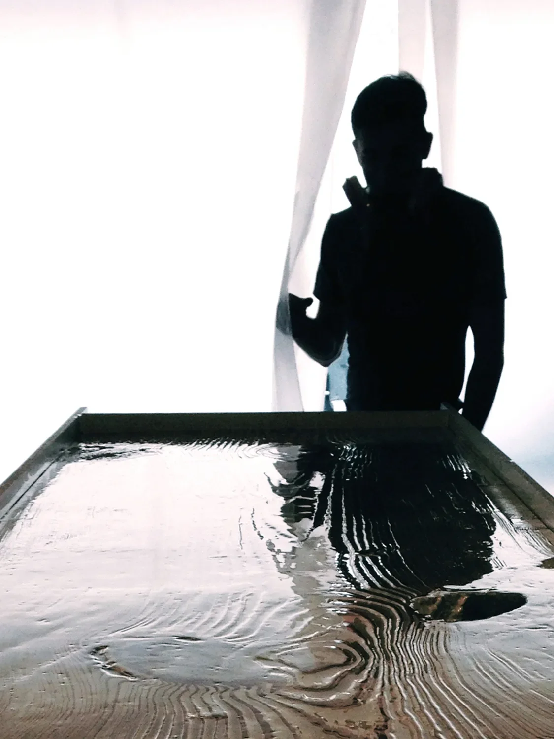 Kyle Preish standing behind a custom tabletop with a reflective, rippled surface