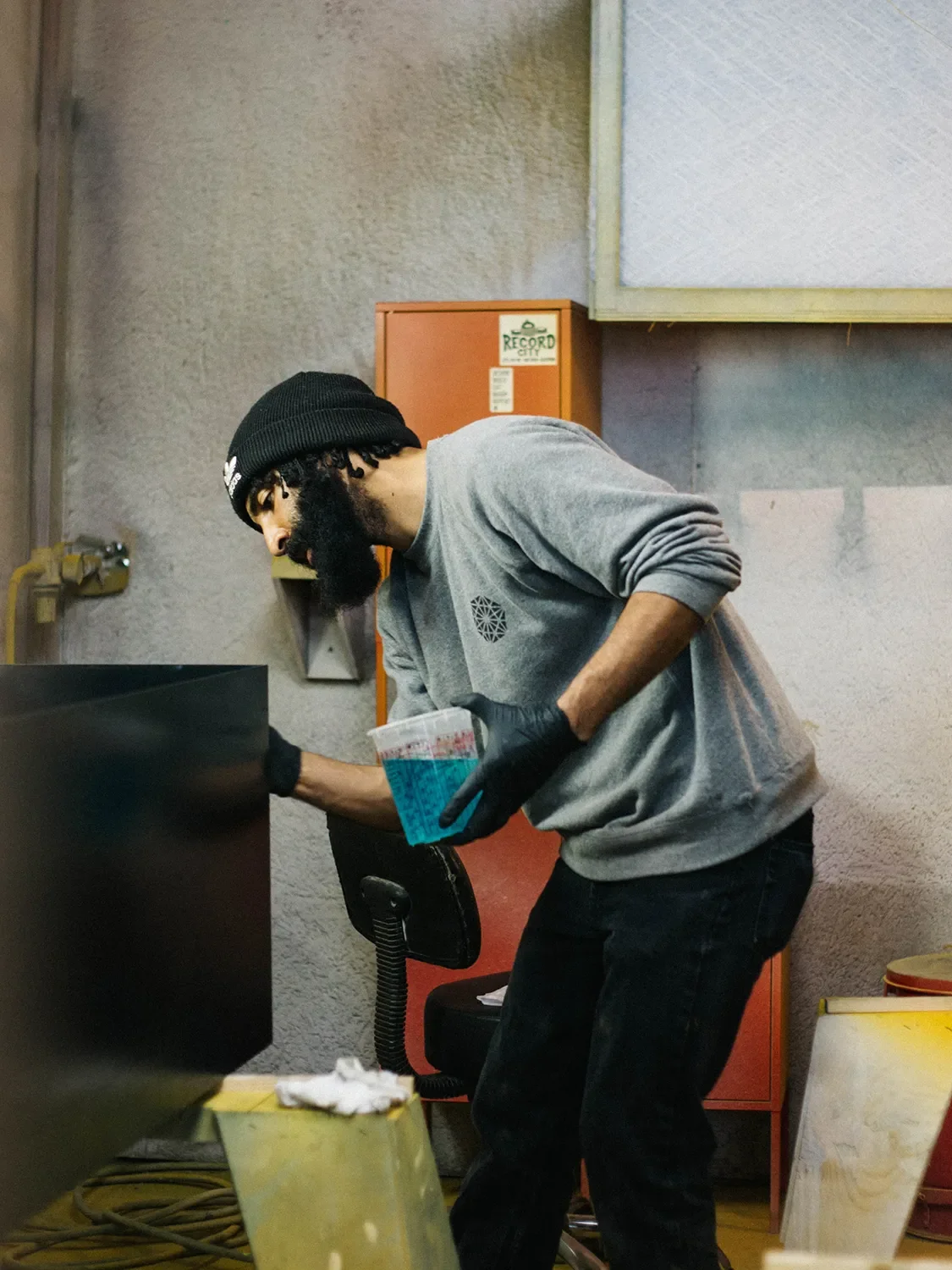 Zack Karas working on a large panel while holding a mixing cup in the Tecture finishing booth