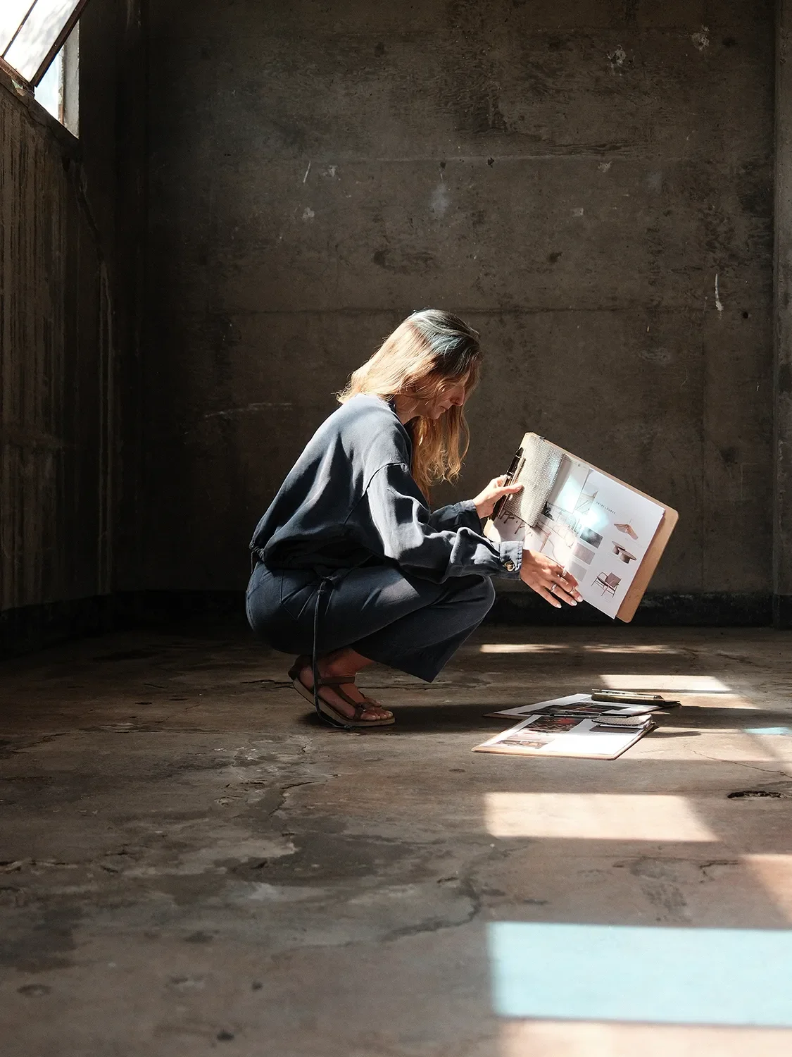 Brittany Cartwright reviewing material samples in an unfinished concrete interior in the back space of Tecture Studio