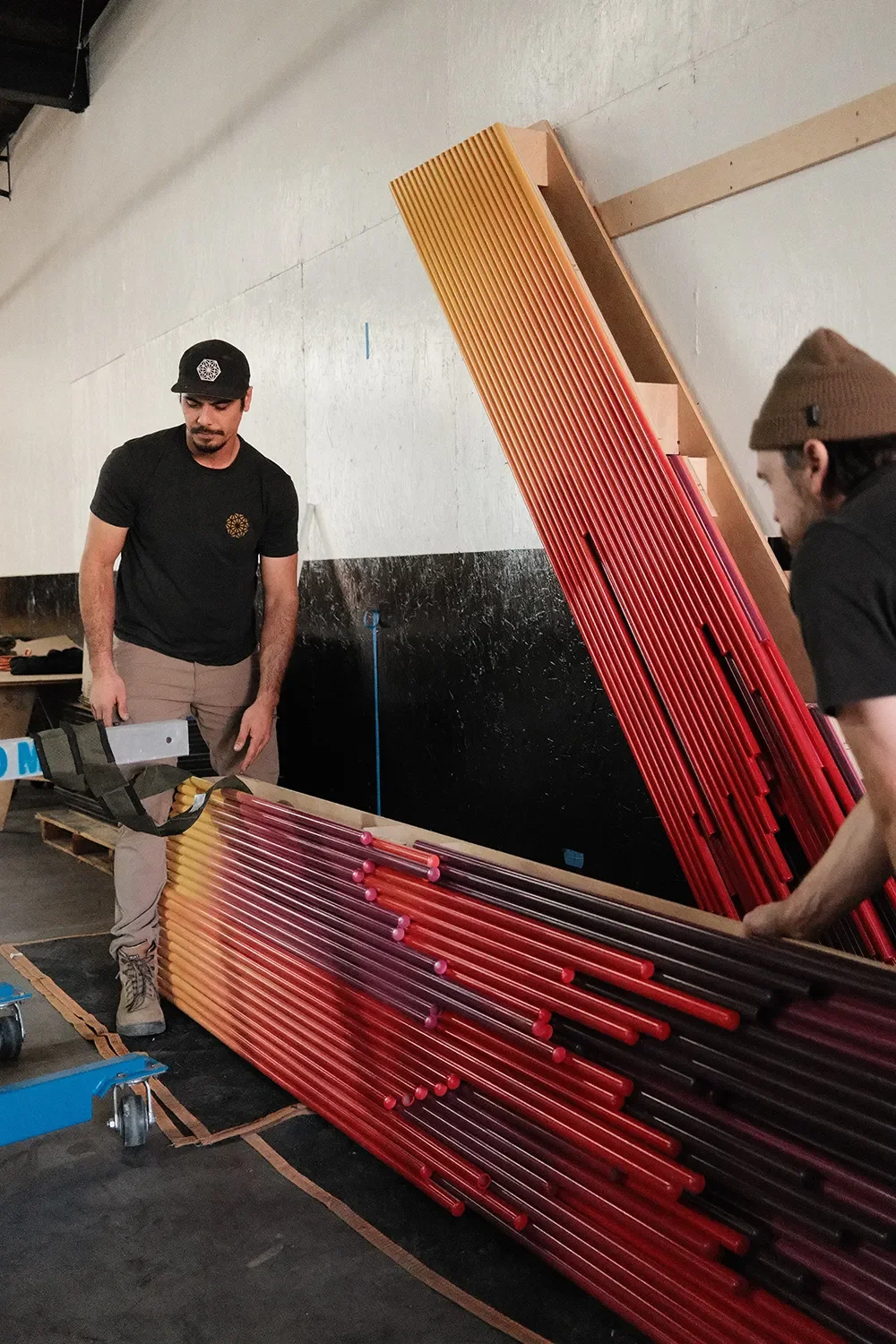 Two Tecture AF fabricators assembling bundled red and orange pvc pipes for The Glitch art dry-fit assembly for UCSD