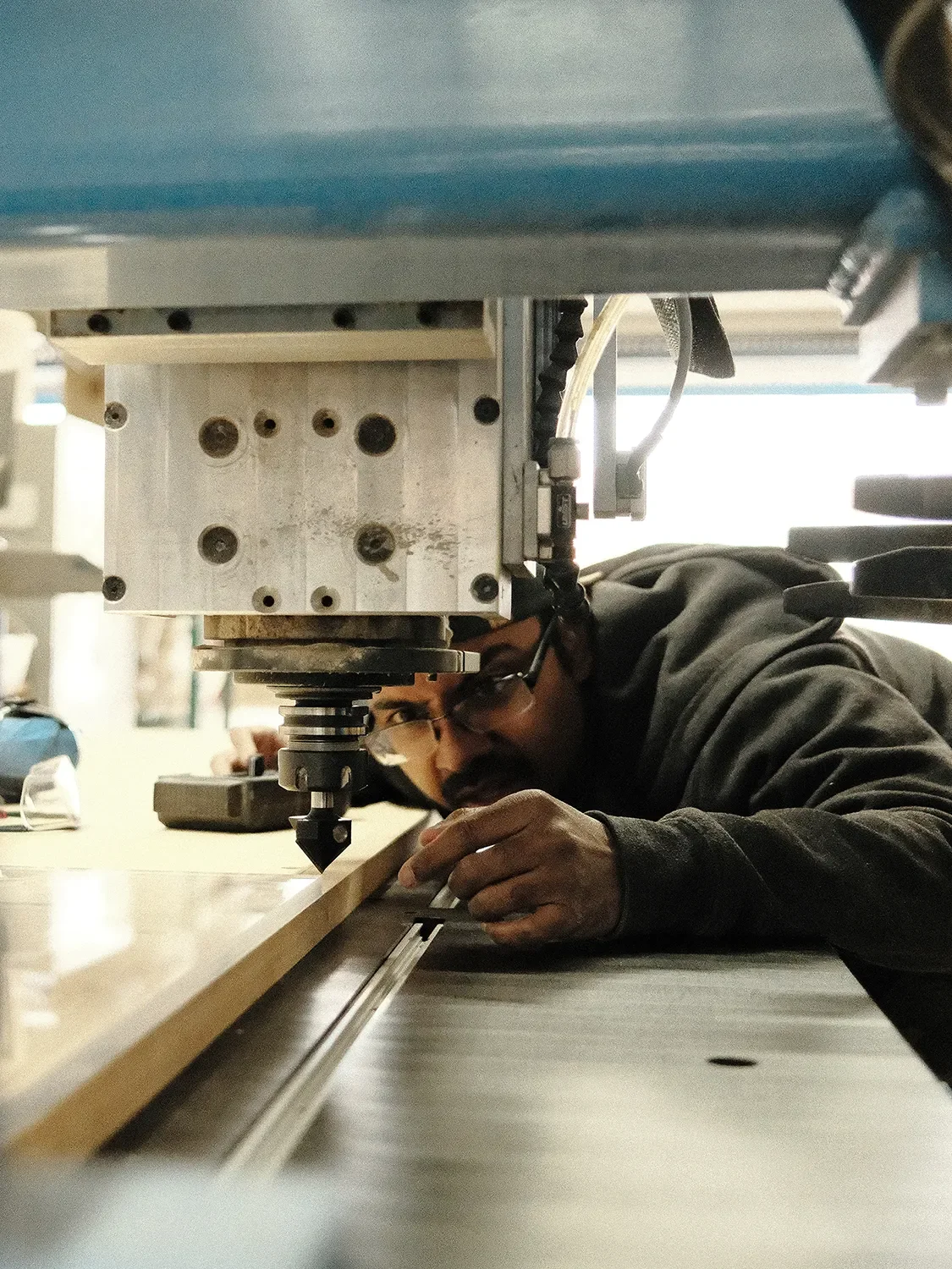 Subrato Roy aligning a wooden commponent beneath the spindle of a CNC router in the Tecture AF shop