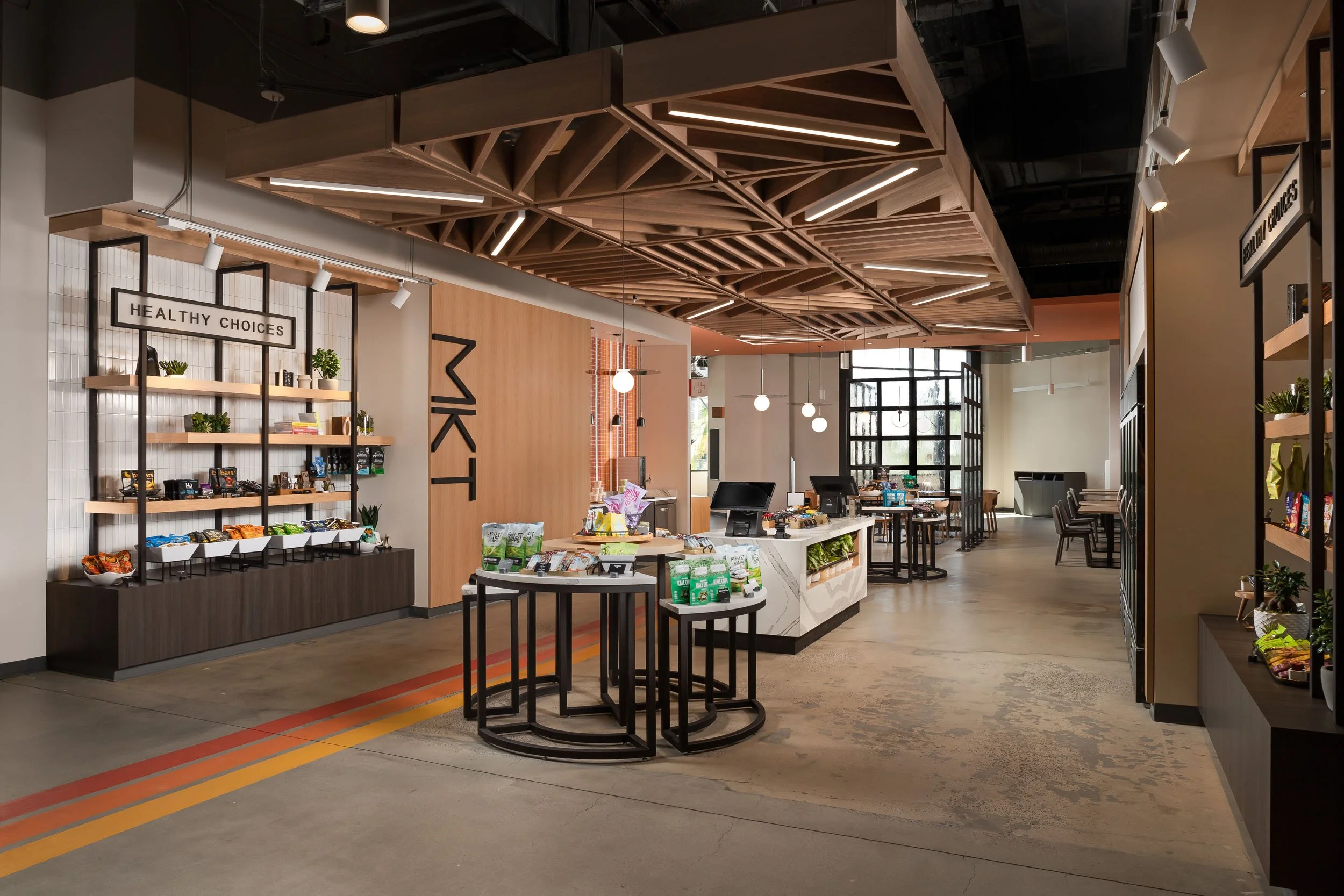 A corporate office cafe beneath a custom wood slat ceiling feature, and a custom striped floor graphic. 
