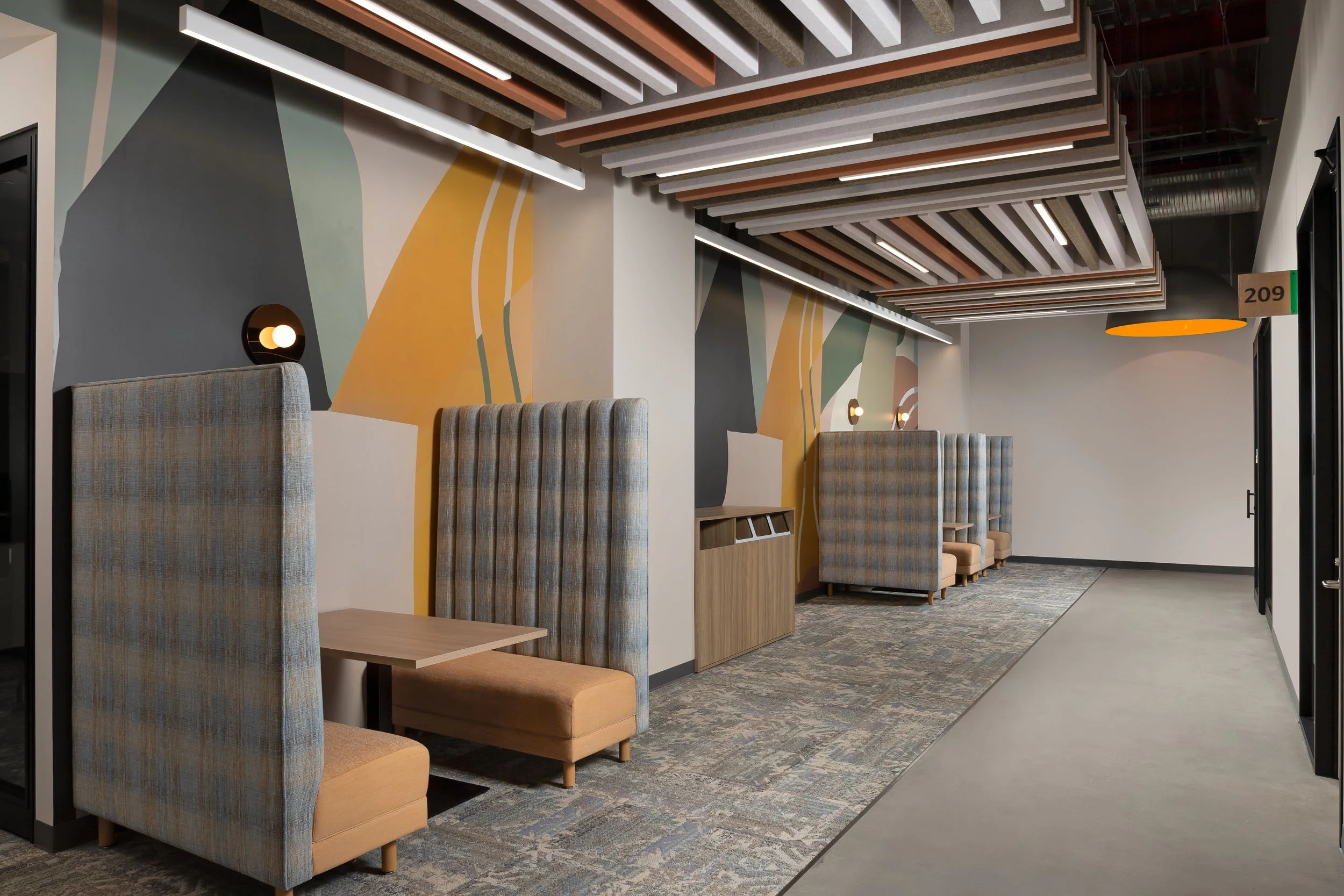 Custom booth seating beside a custom wall graphic in an open corporate office space with a custom suspended ceiling feature.
