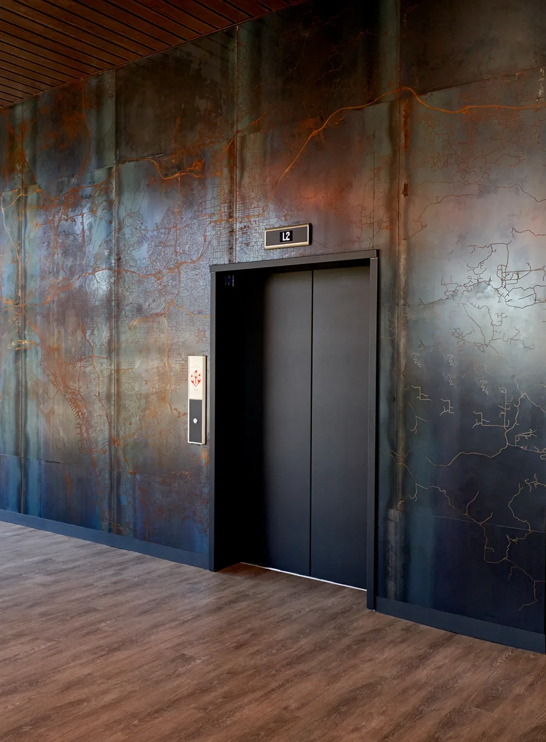 Corten metal elevator wall cladding with acid etched map across the entire installation in San Diego