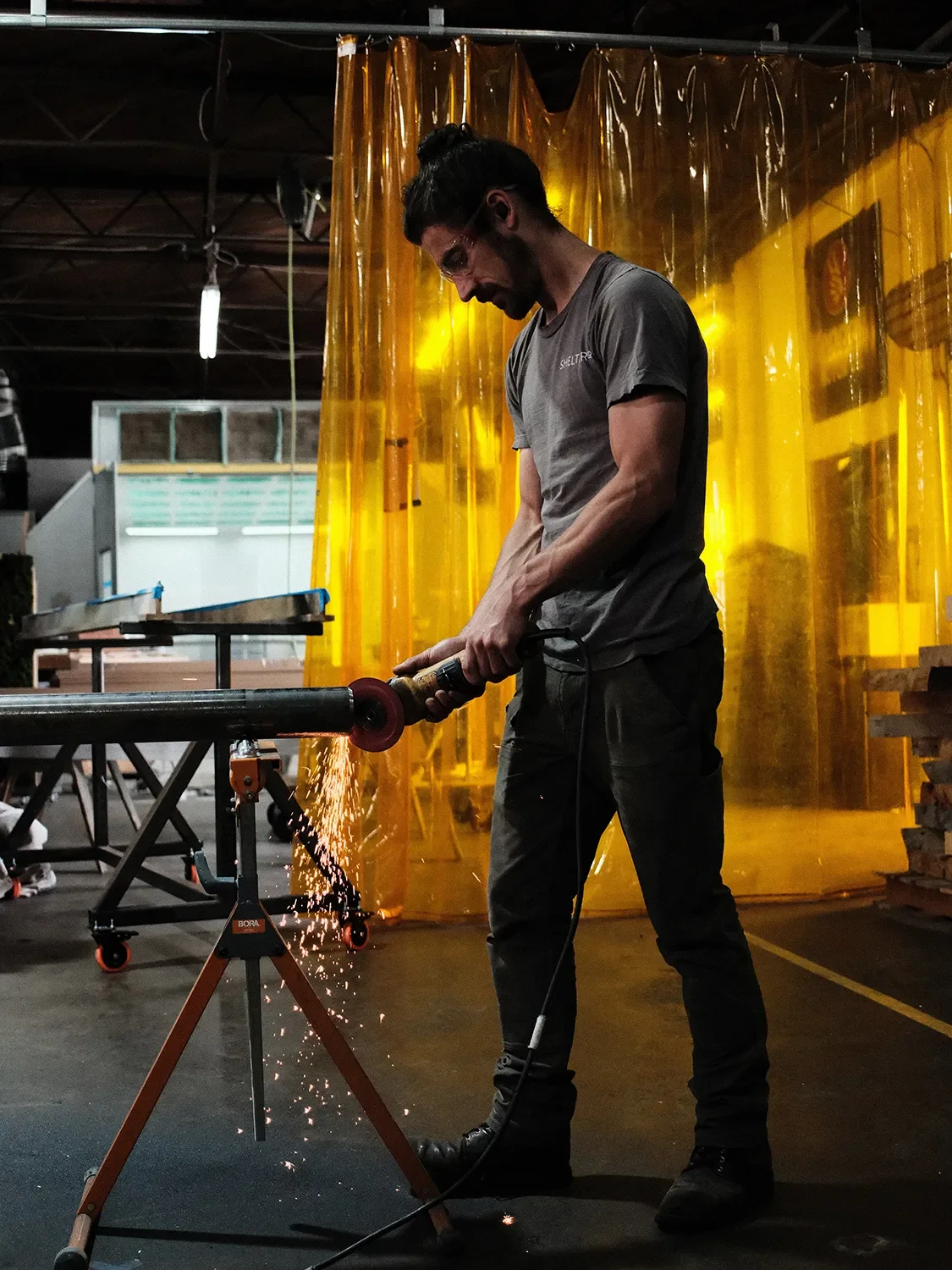 Chris Clover grinding a steel tube, sending sparks across the Tecture AF shop