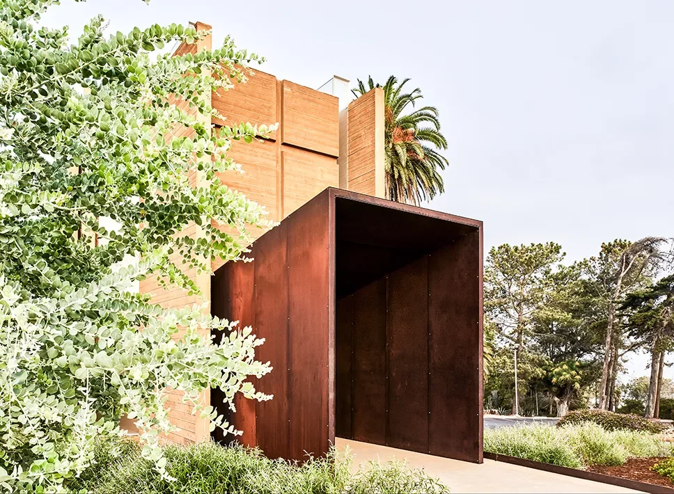 Weathering steel entry portal set into the wood clad facade of Prescott Chapel in San Diego
