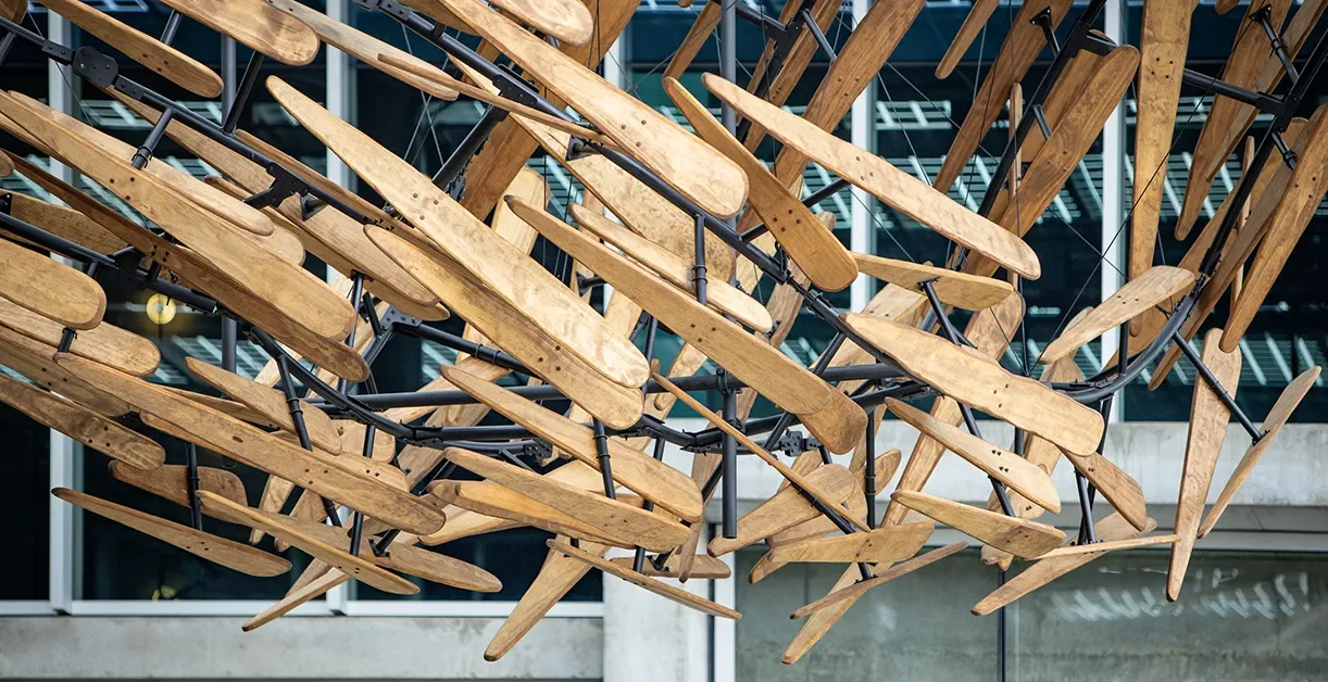 Migration, suspended wood members on a black steel armature above an open stairway on a Torrey Pines campus
