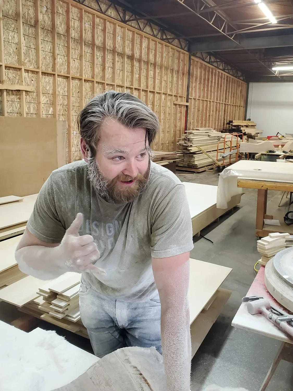 Slade Fischer covered in resin dust and making a shaka gesture in the Tecture shop