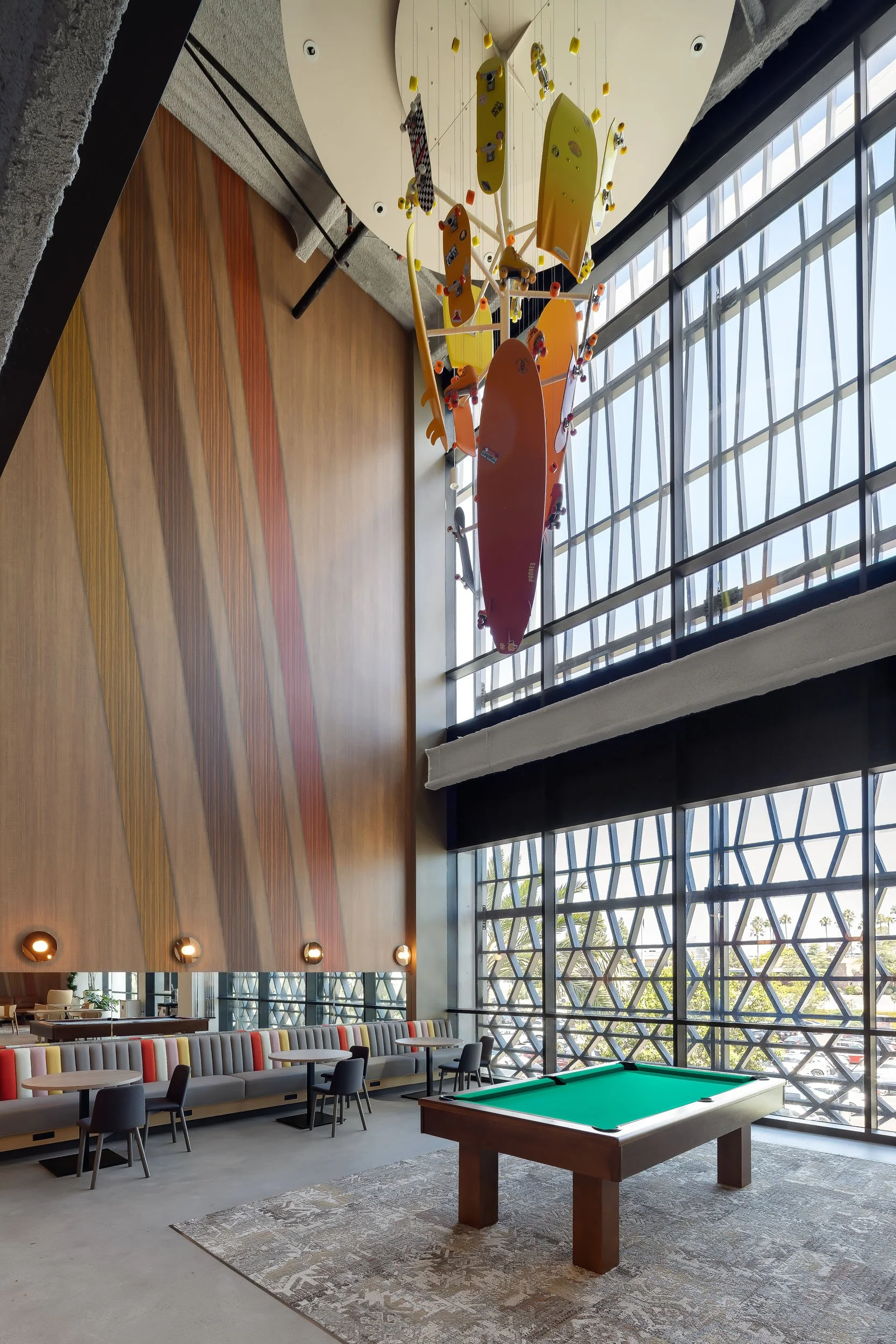 A double-height corporate office recreation space with a custom fabricated colorful hanging sculpture over a pool table.