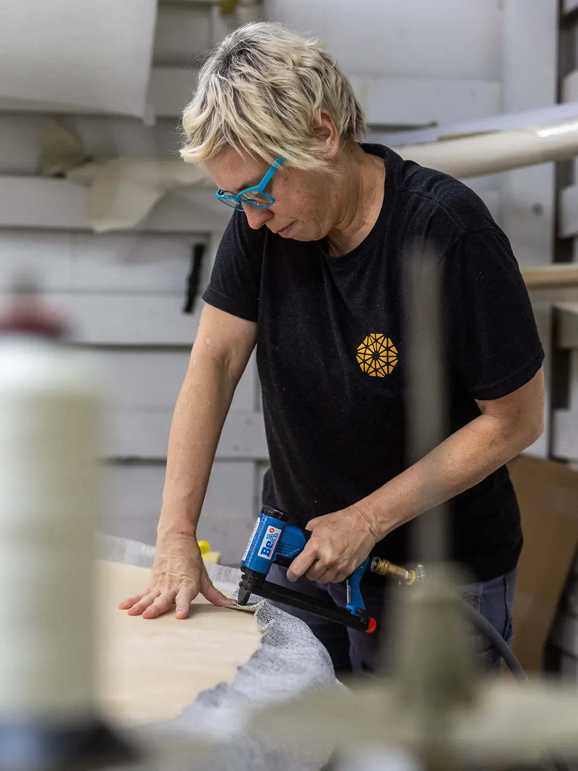 Molly Whittaker using a pneumatic stapler to attach upholstery fabric to a custom furniture component