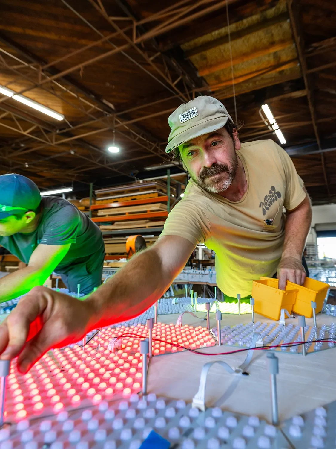 Zachary Wilkie adjusting and assembling a colorful LED lighting components on a custom feature 