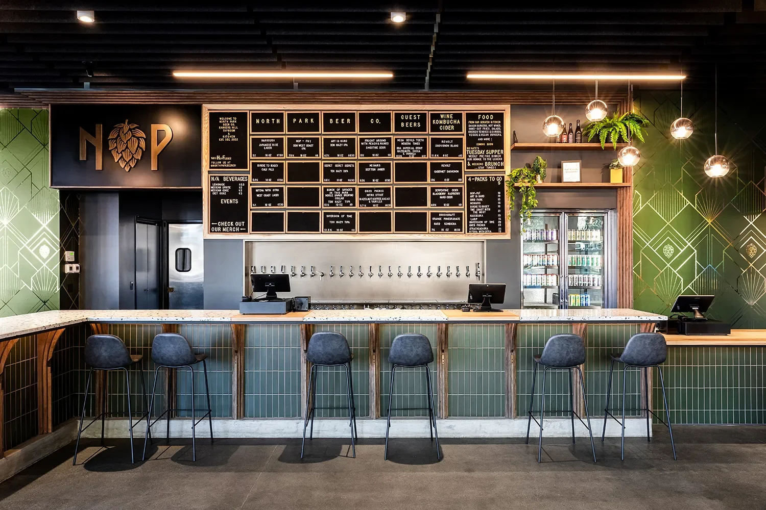 Custom bar and back bar tap wall at North Park Beer Co in Bankers Hill San Diego, with dark wood and green tile, and a custom green and brass wallpaper