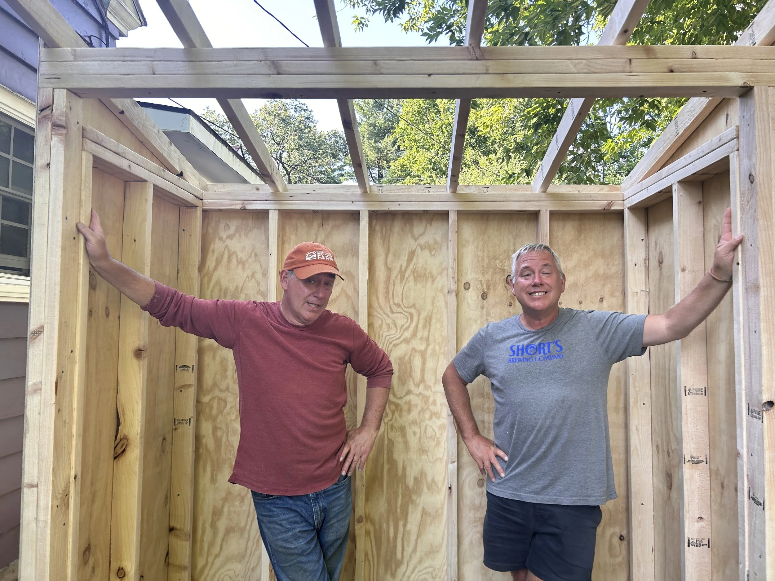 Two men standing inside a wooden frame structure under construction.
