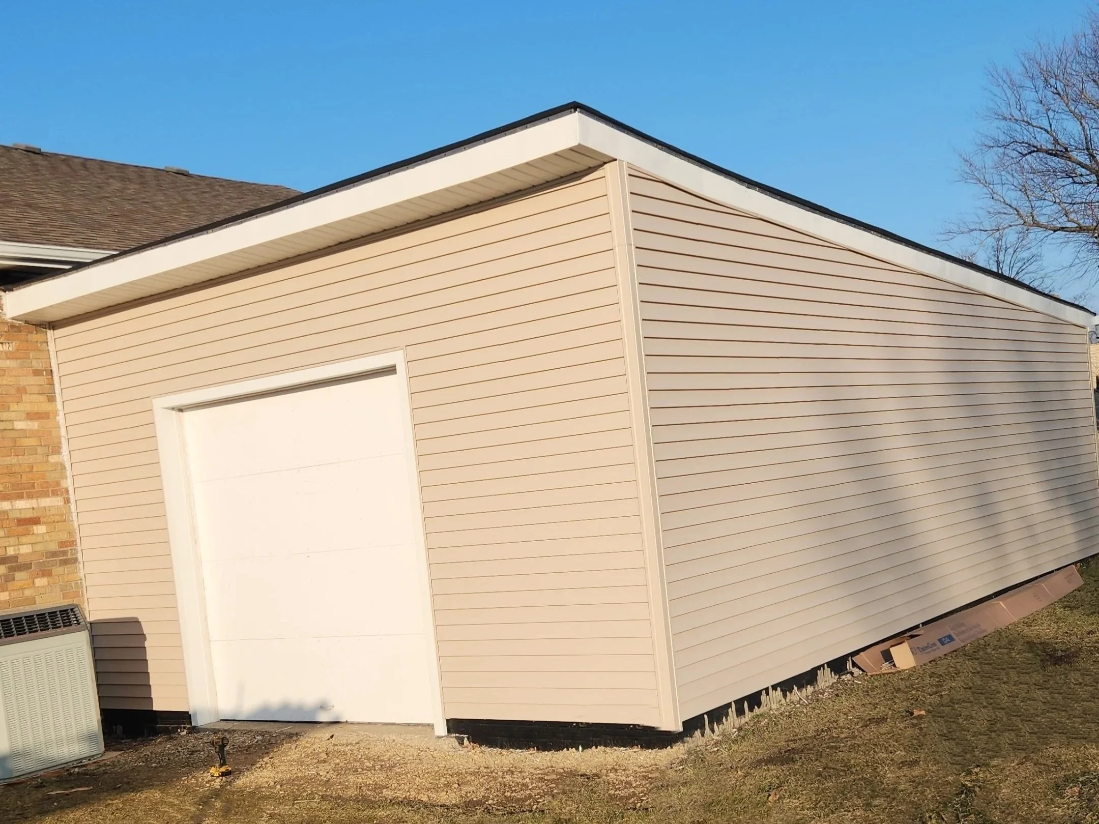 Beige shed with a white door next to a brick building