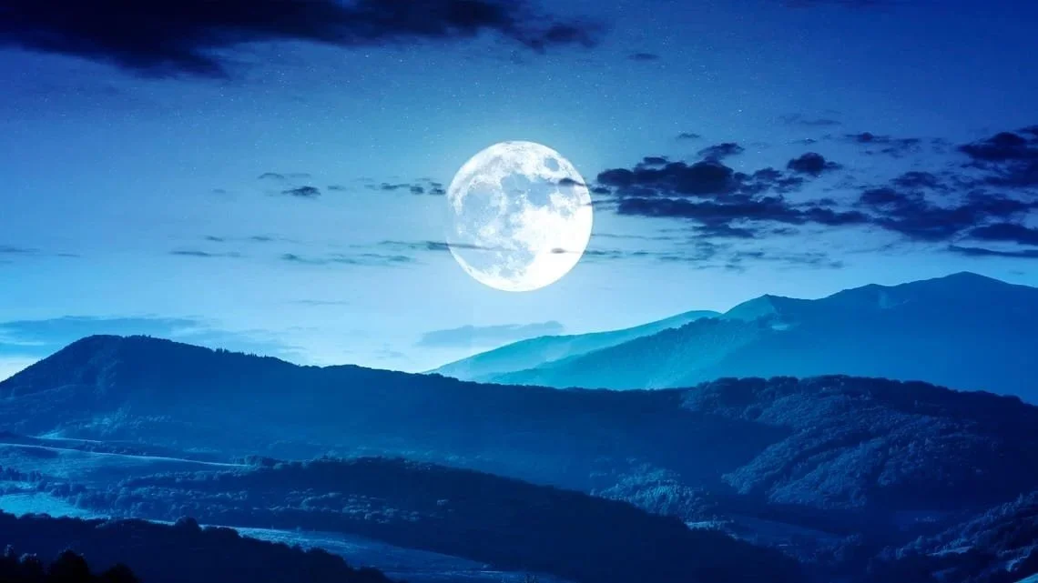 Giant blue moon over low mountains