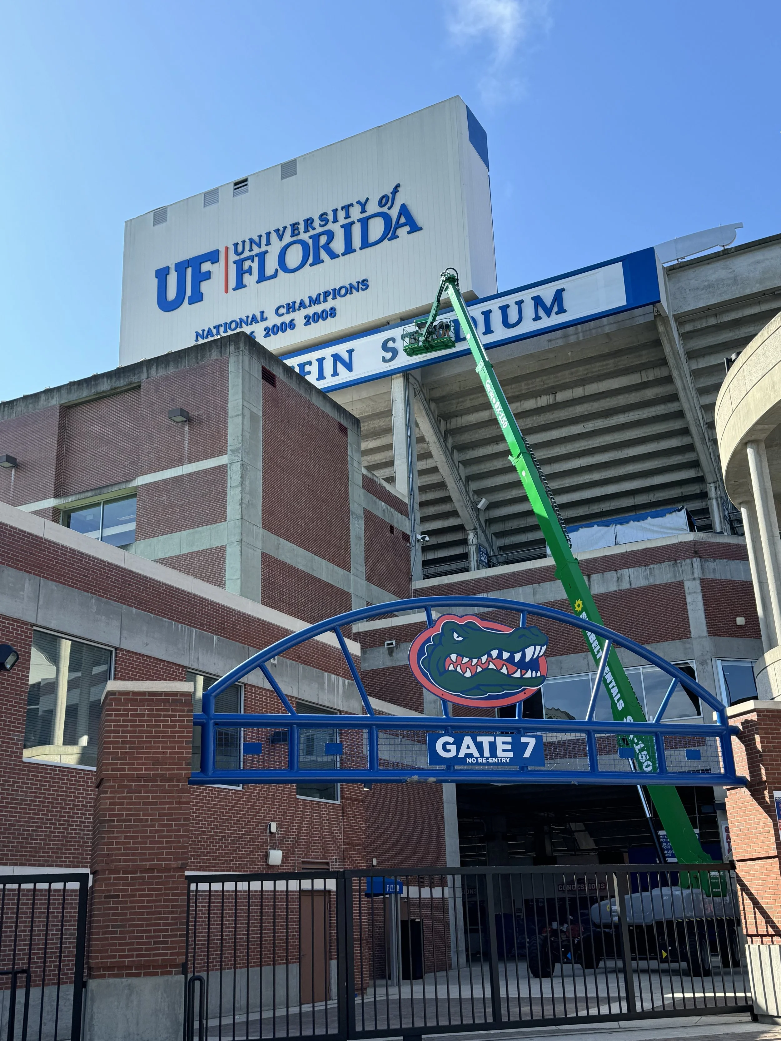 Sign installation at entrance gate to the University of Florida football stadium