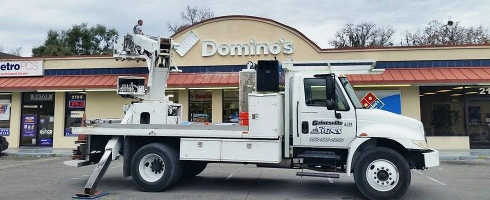 Technician using a truck to repair a Domino’s sign