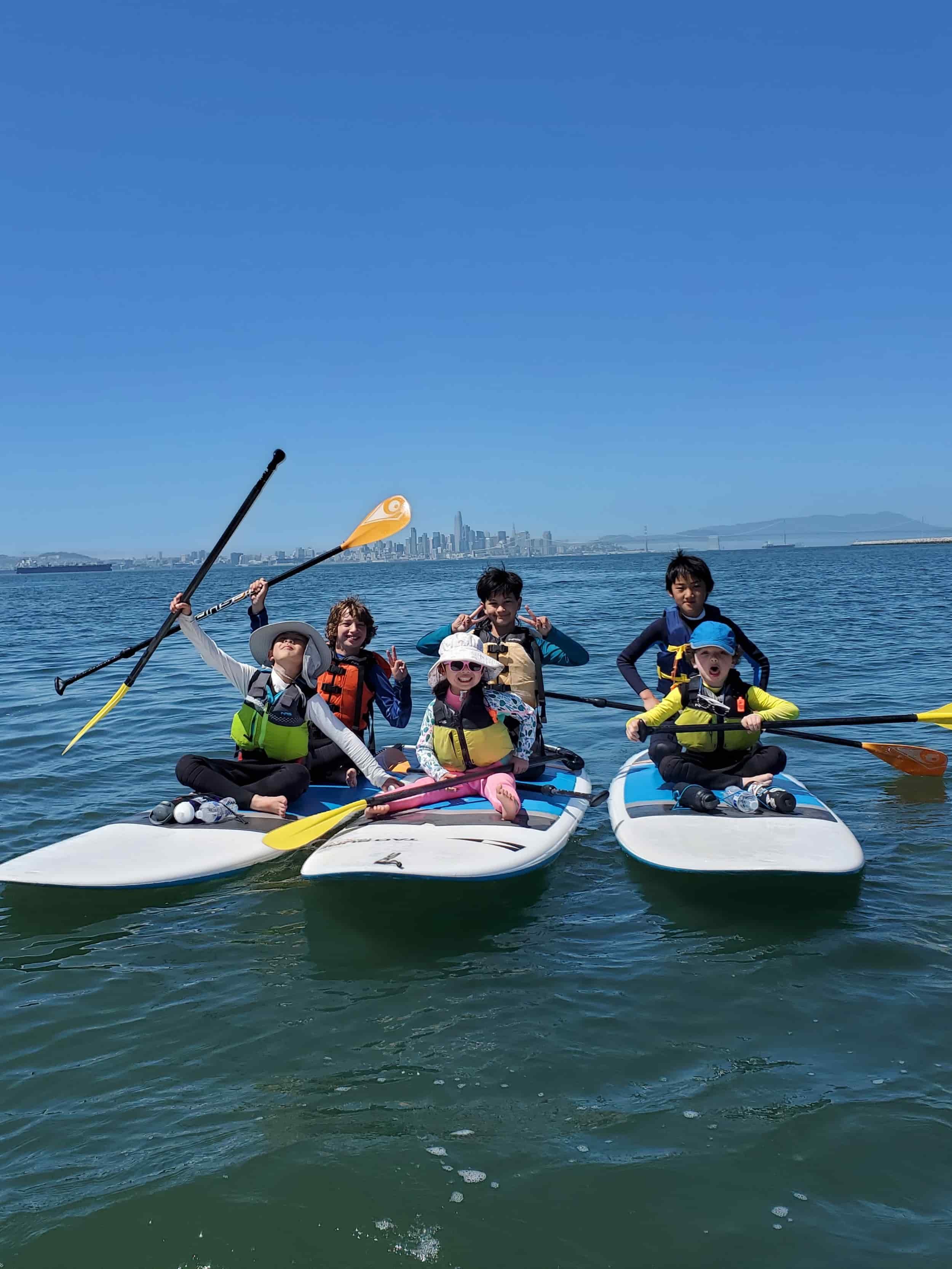 Group of children at summer camp stand-up paddleboarding on the San Francisco Bay.