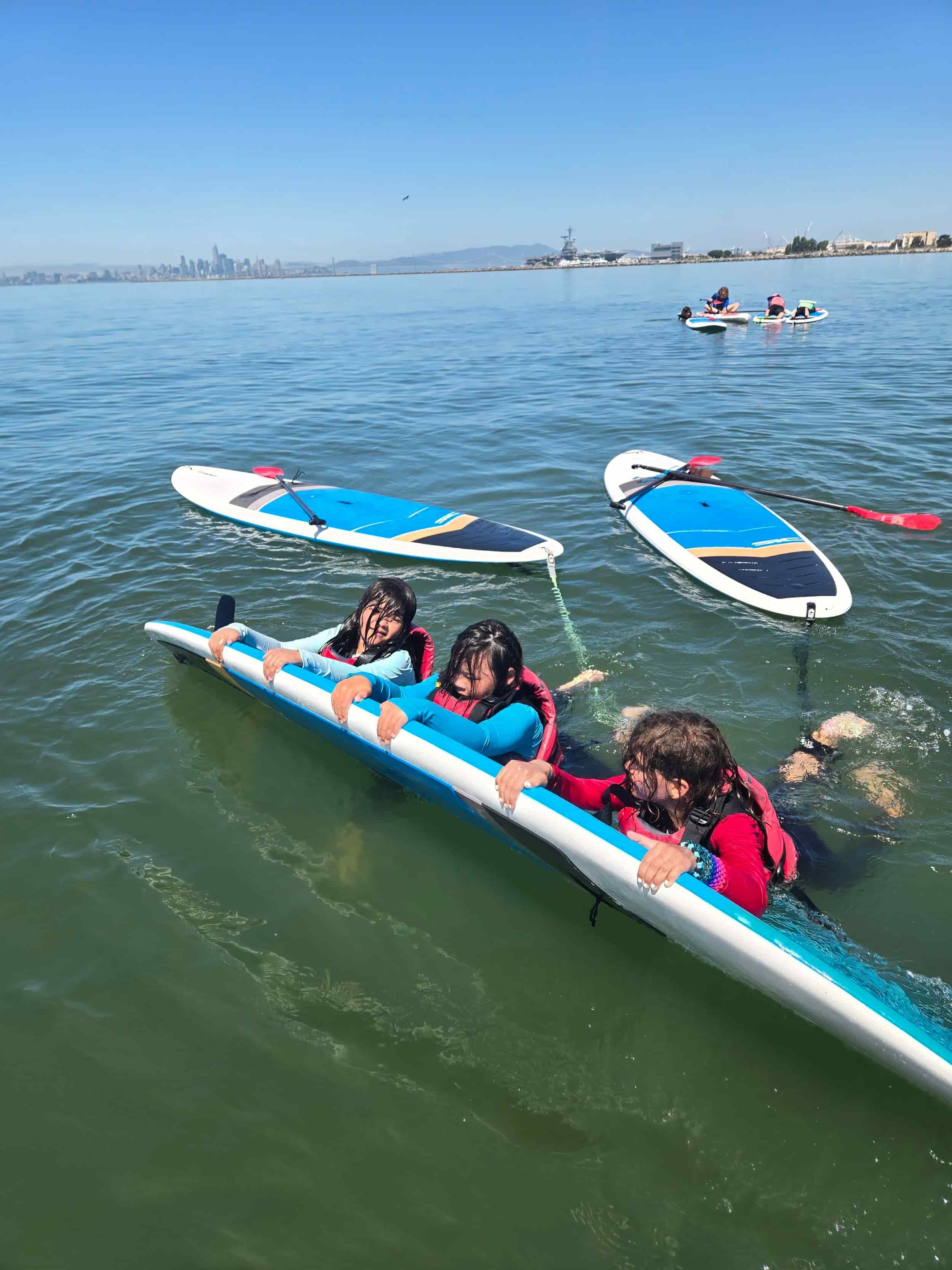 Kids practicing paddleboarding safety skills for summer camp.