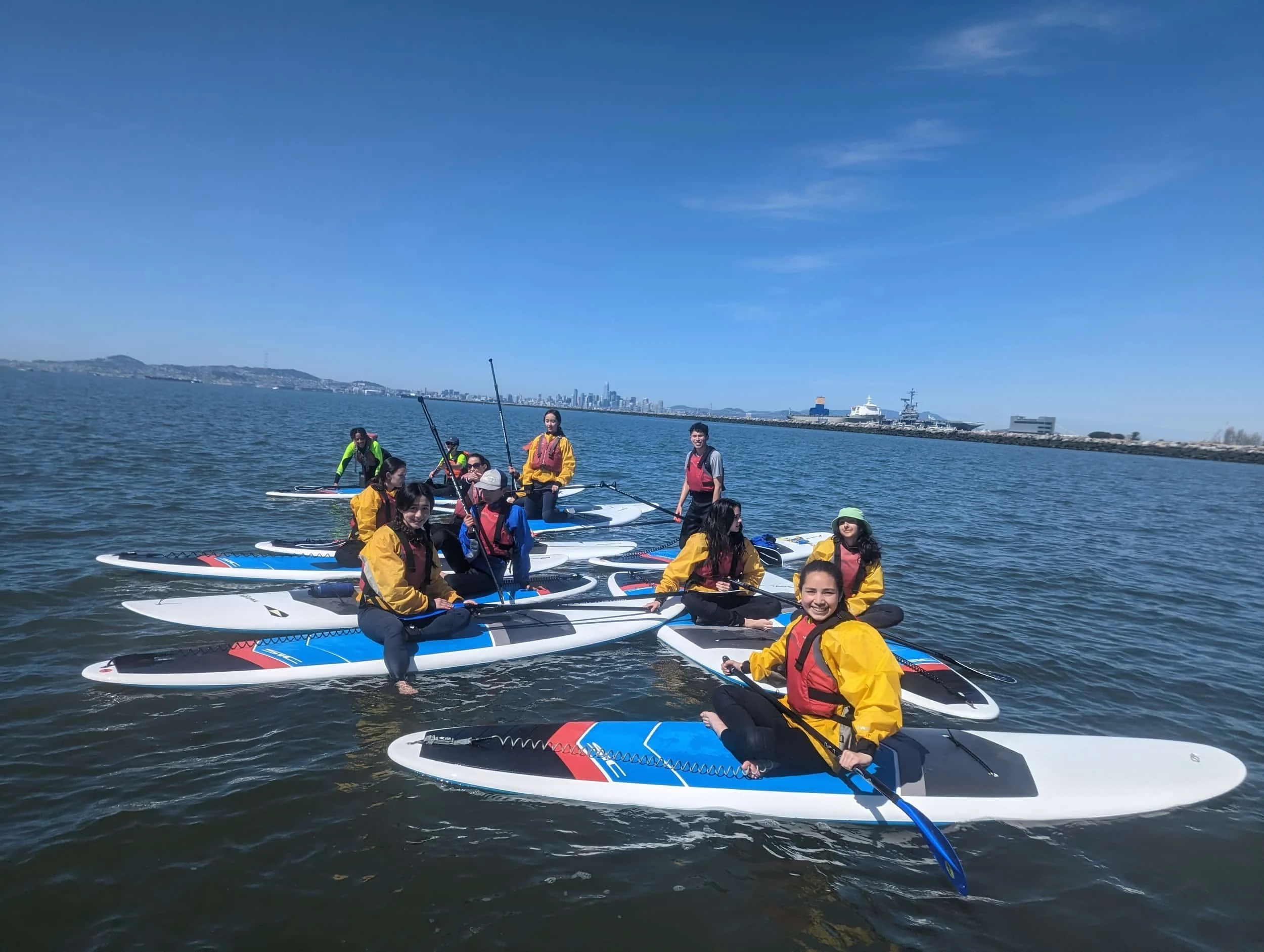 A group of kids having fun on paddleboards in the East Bay for summer camp.