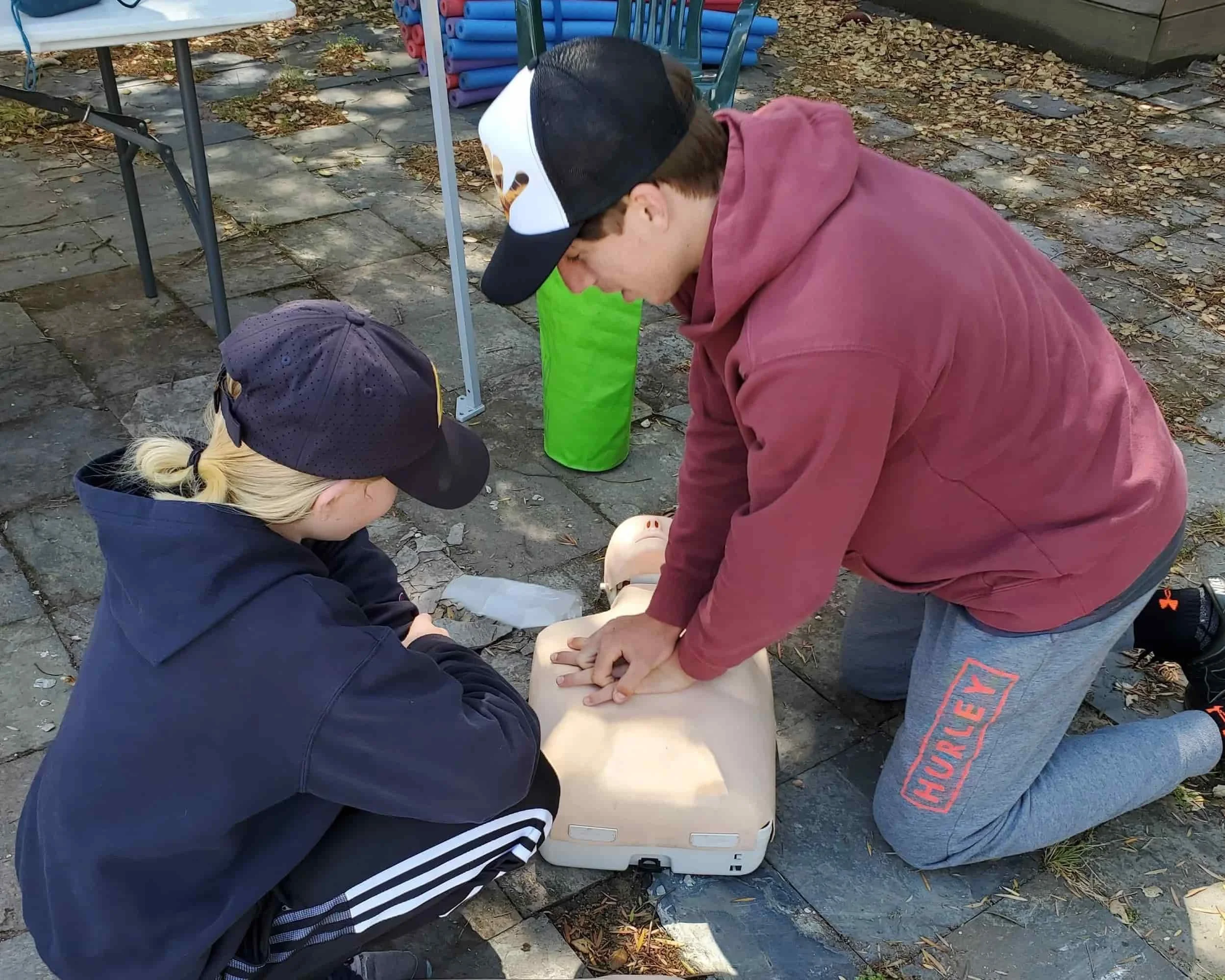 Two people practicing CPR on a training dummy for the leadership training to get their CRP and first aid certification.