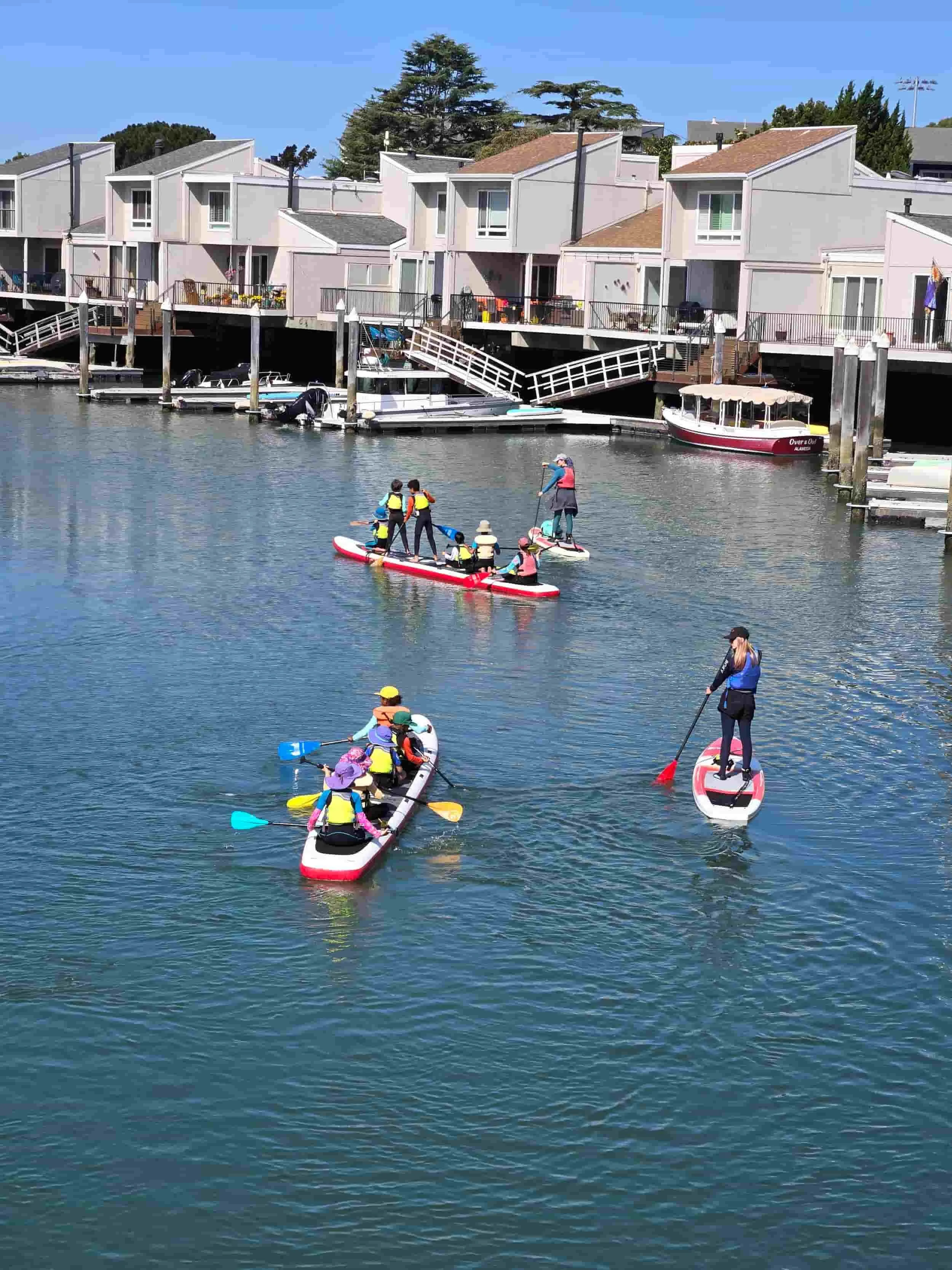 Kids paddleboarding and kayaking on calm waters in the best east bay summer camp Gaia Guides Kids Camp .