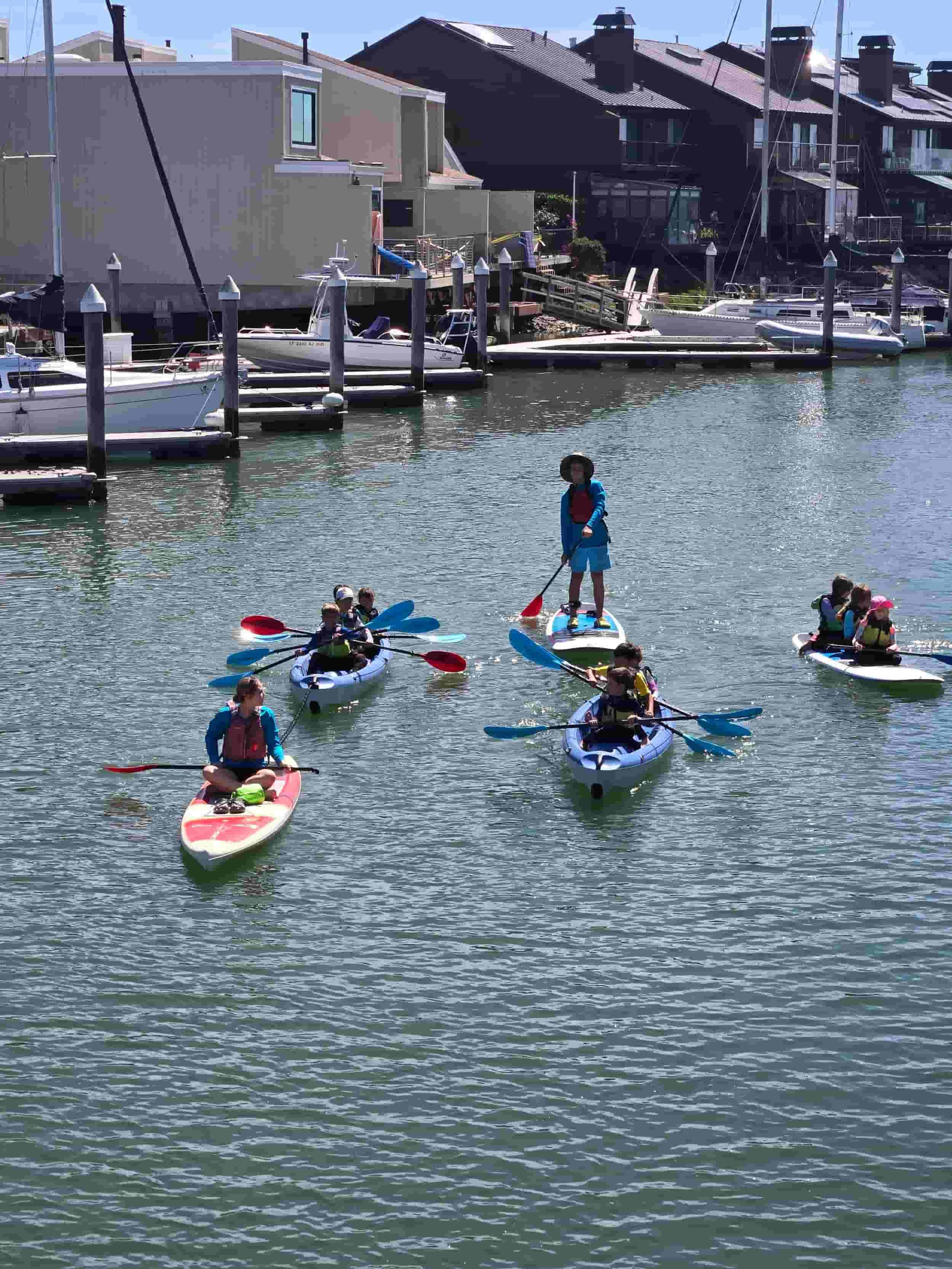 Children and expert instructors paddleboarding for outdoor adventure summer camp in the Bay Area.