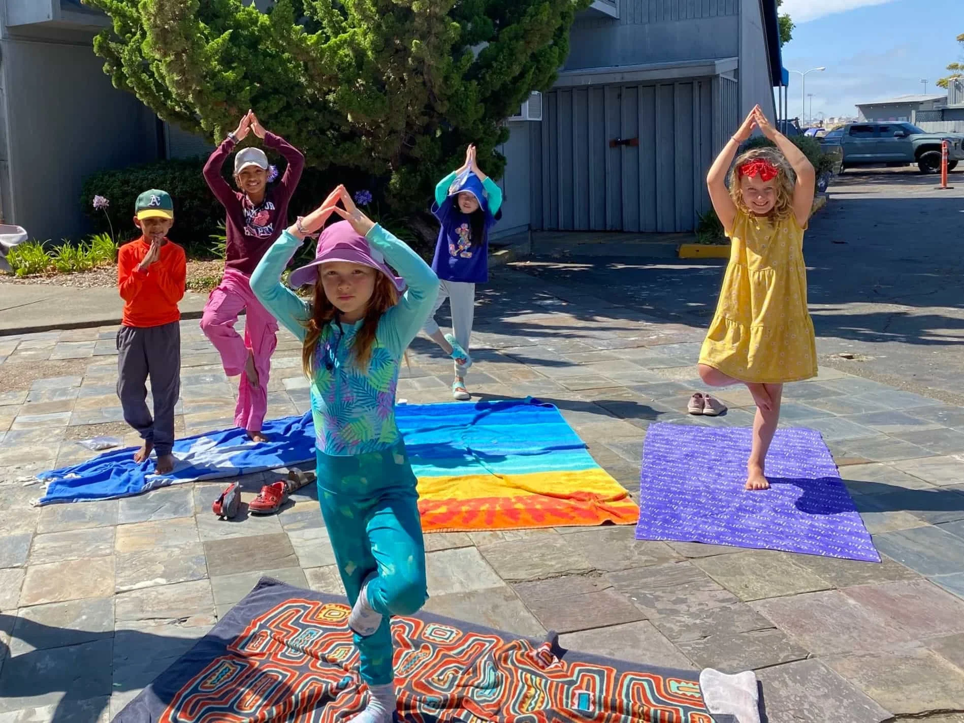 Children practicing yoga outdoors in Alameda summer camp.