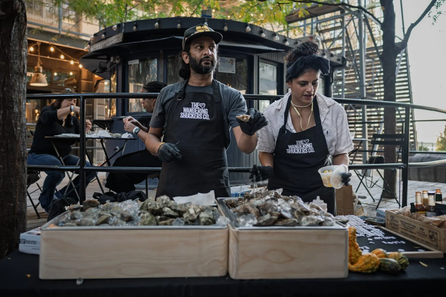 Rutvik Patel and Mahnaz Damania serving oysters at an outdoor raw bar market stall