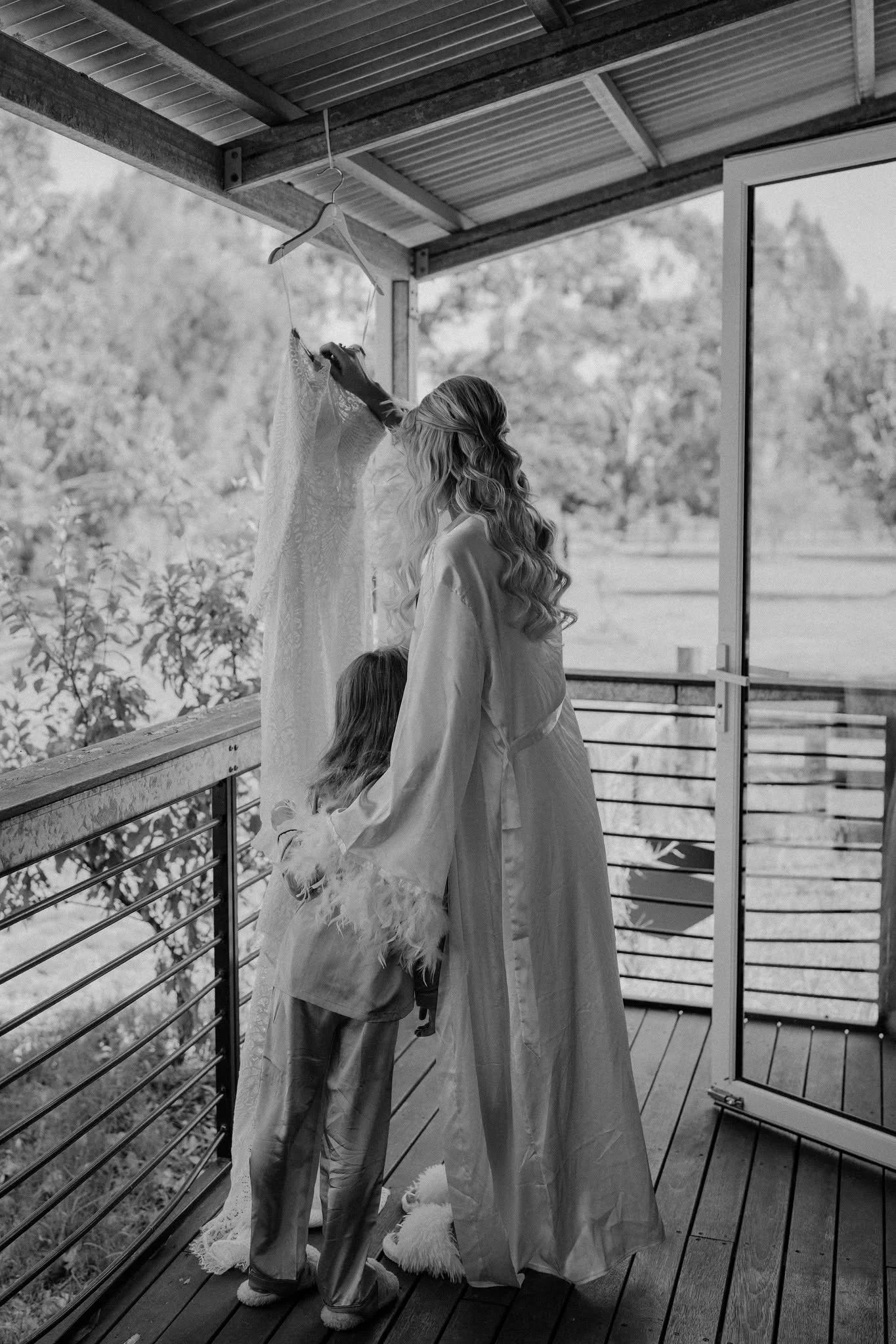 Bride-to-be and child viewing a lace wedding dress at an outdoor wedding location