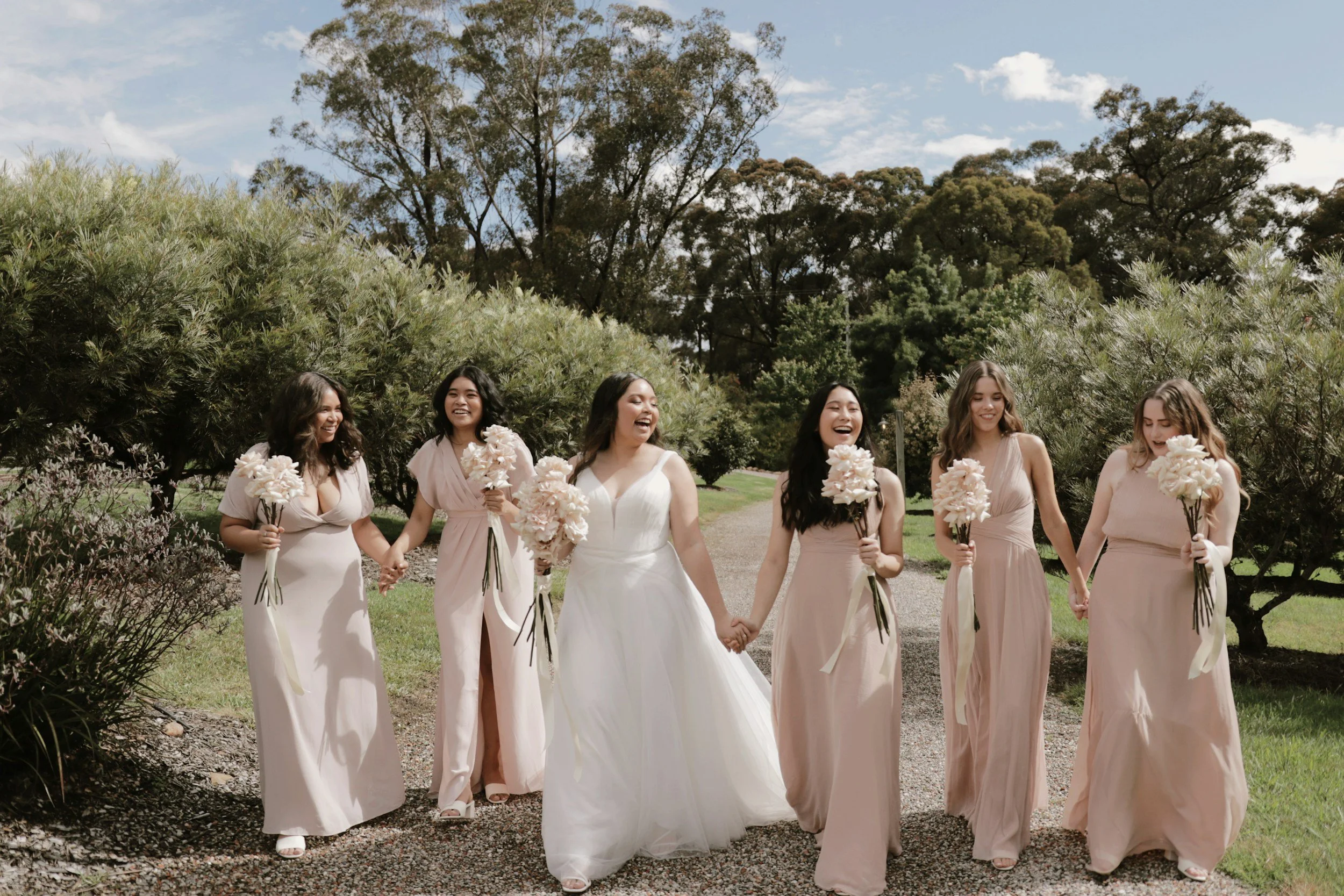 Bride and bridesmaids holding bouquets at an outdoor wedding